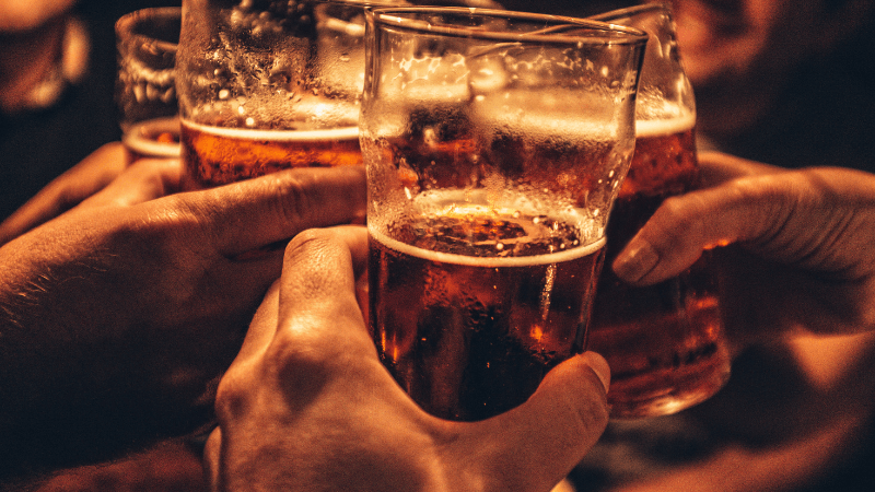 A group of people are toasting with glasses of beer.