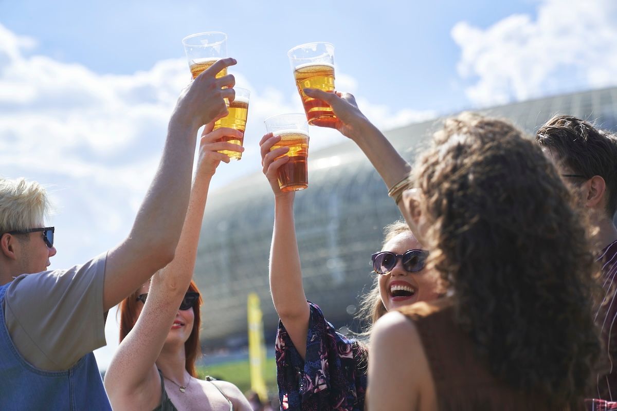 Group of friends toasting with beer outside of a football stadium