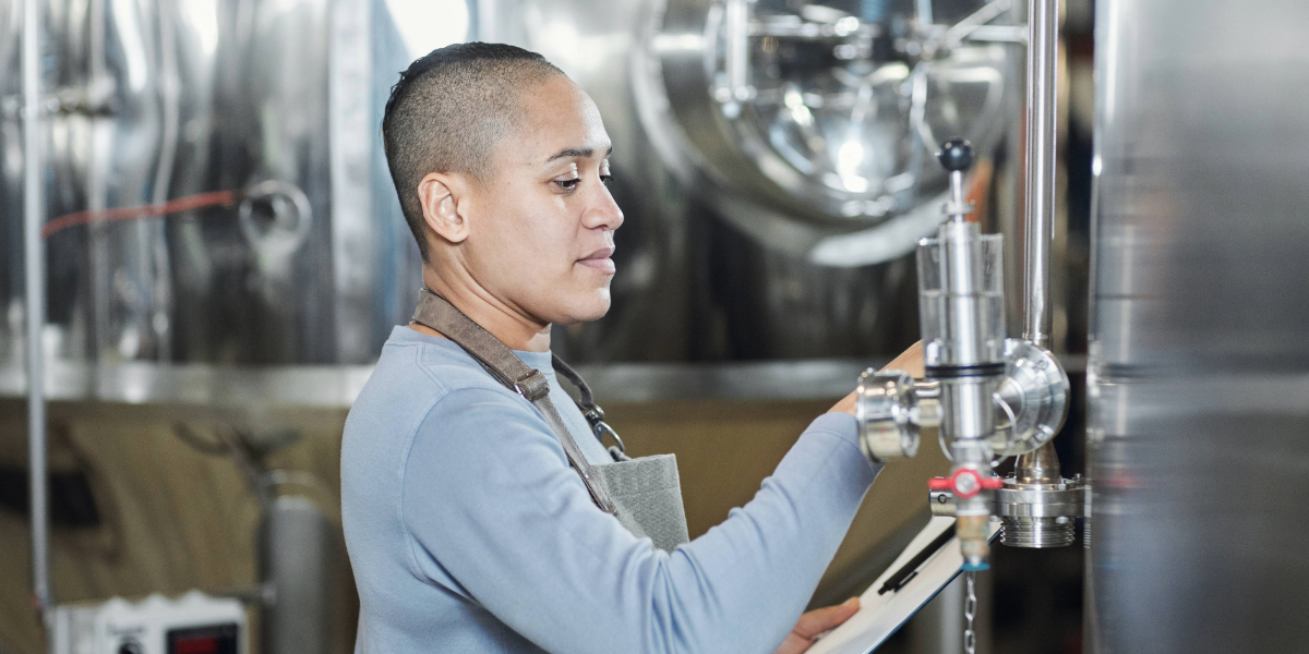 A female brewer working on a tank