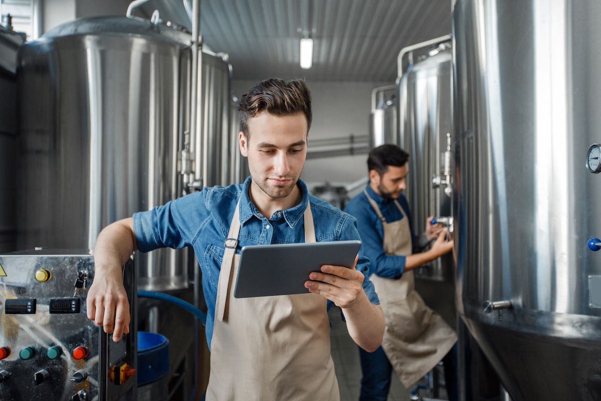 Brewery workers managing production on tablet