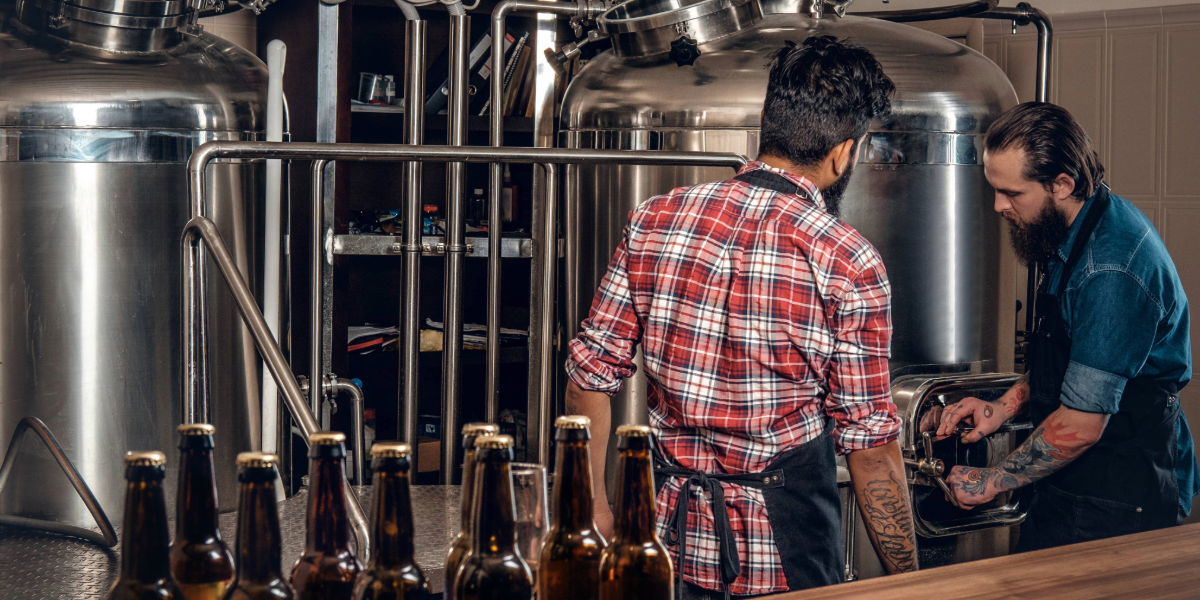 Two men are working in a brewery making beer.