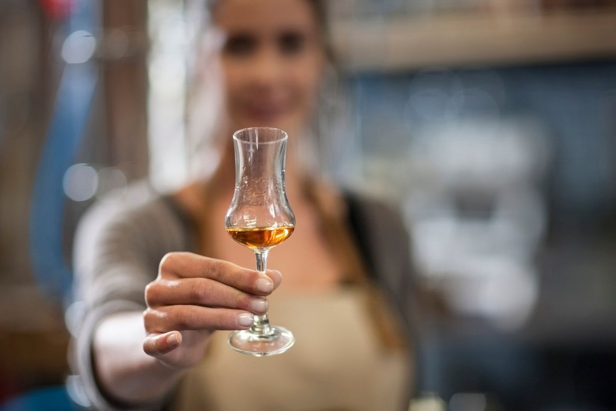 female distiller testing whiskey