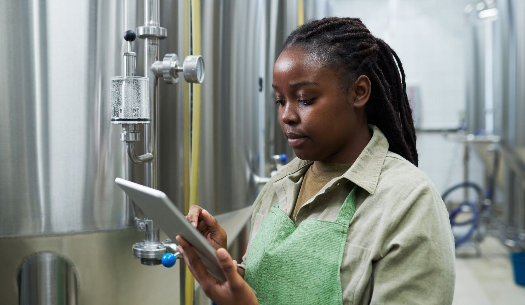Female brewer checking fermentation process on tablet