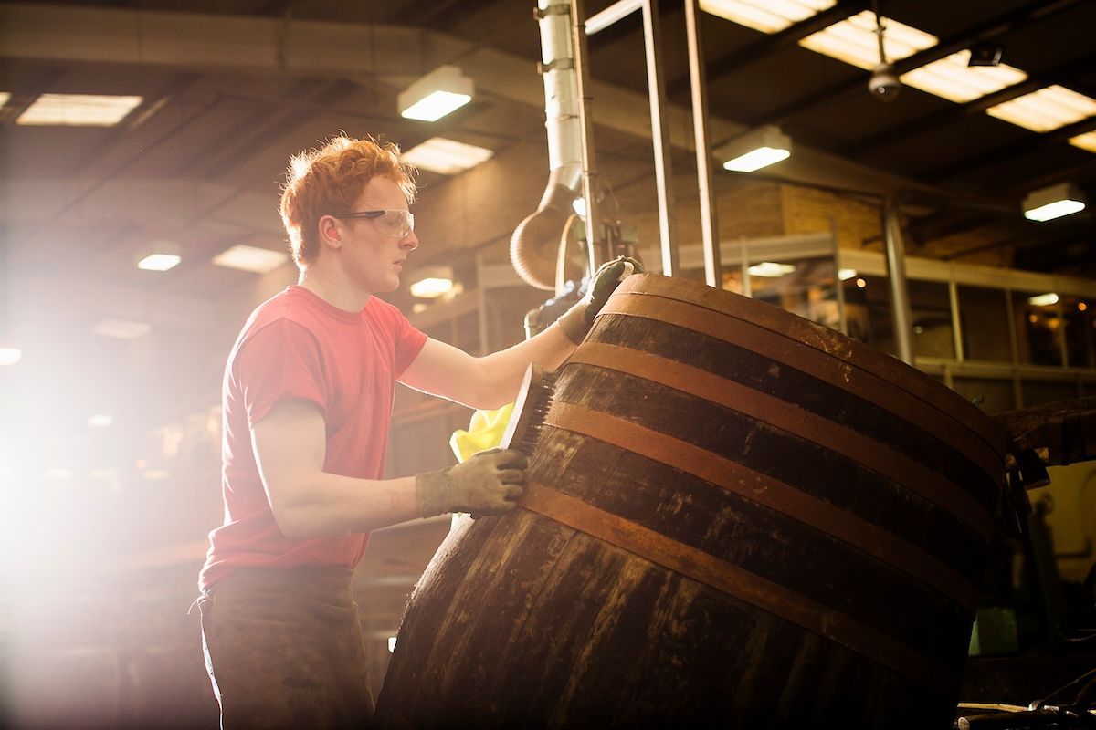 Young distiller working in cooperage 