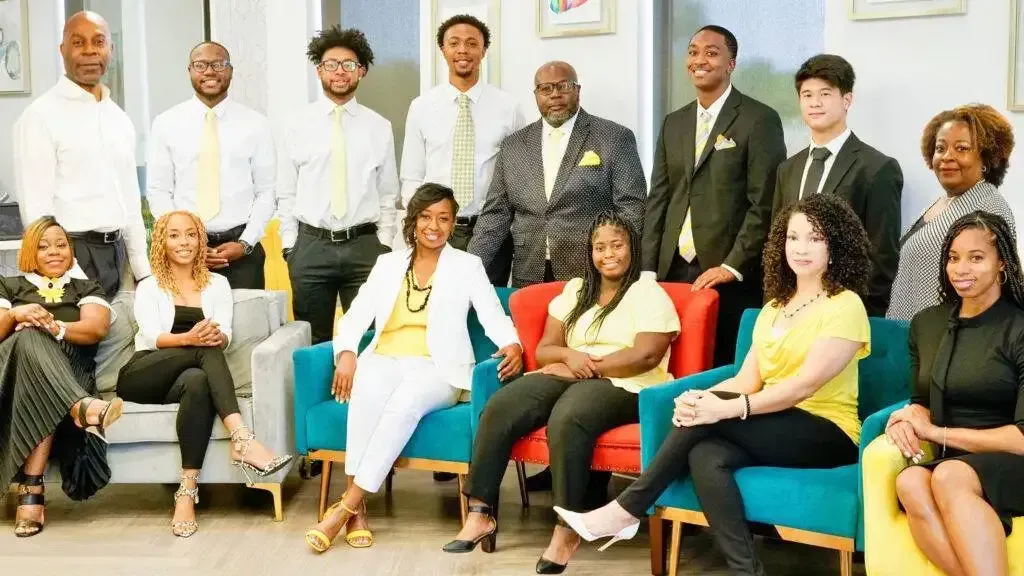 A group of people are posing for a picture while sitting in chairs.