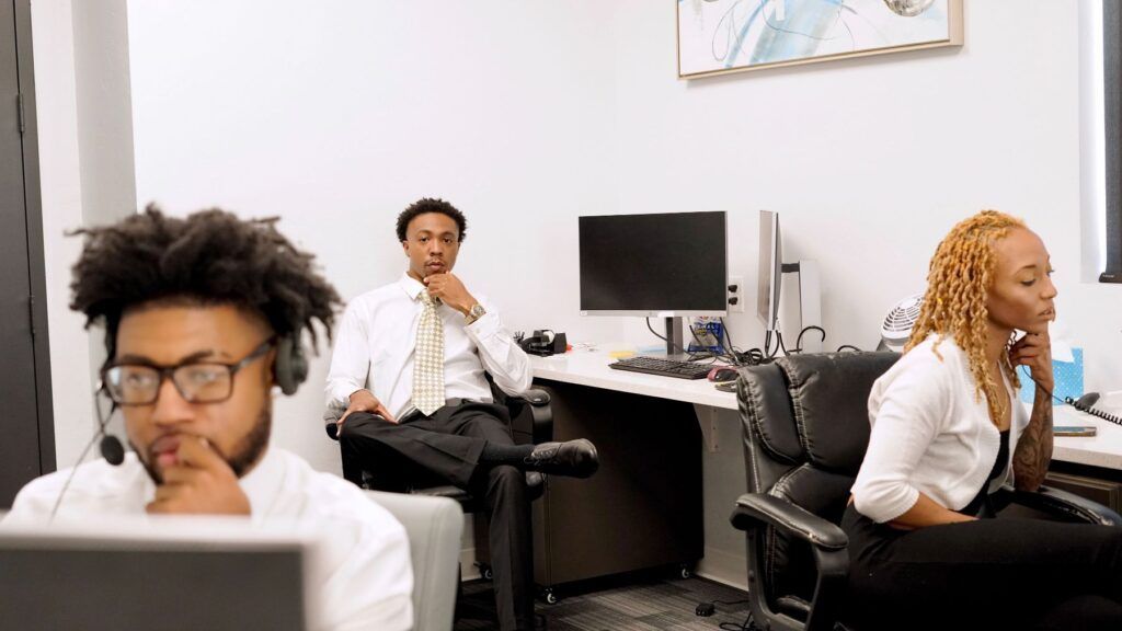 A group of people are sitting at desks in an office.