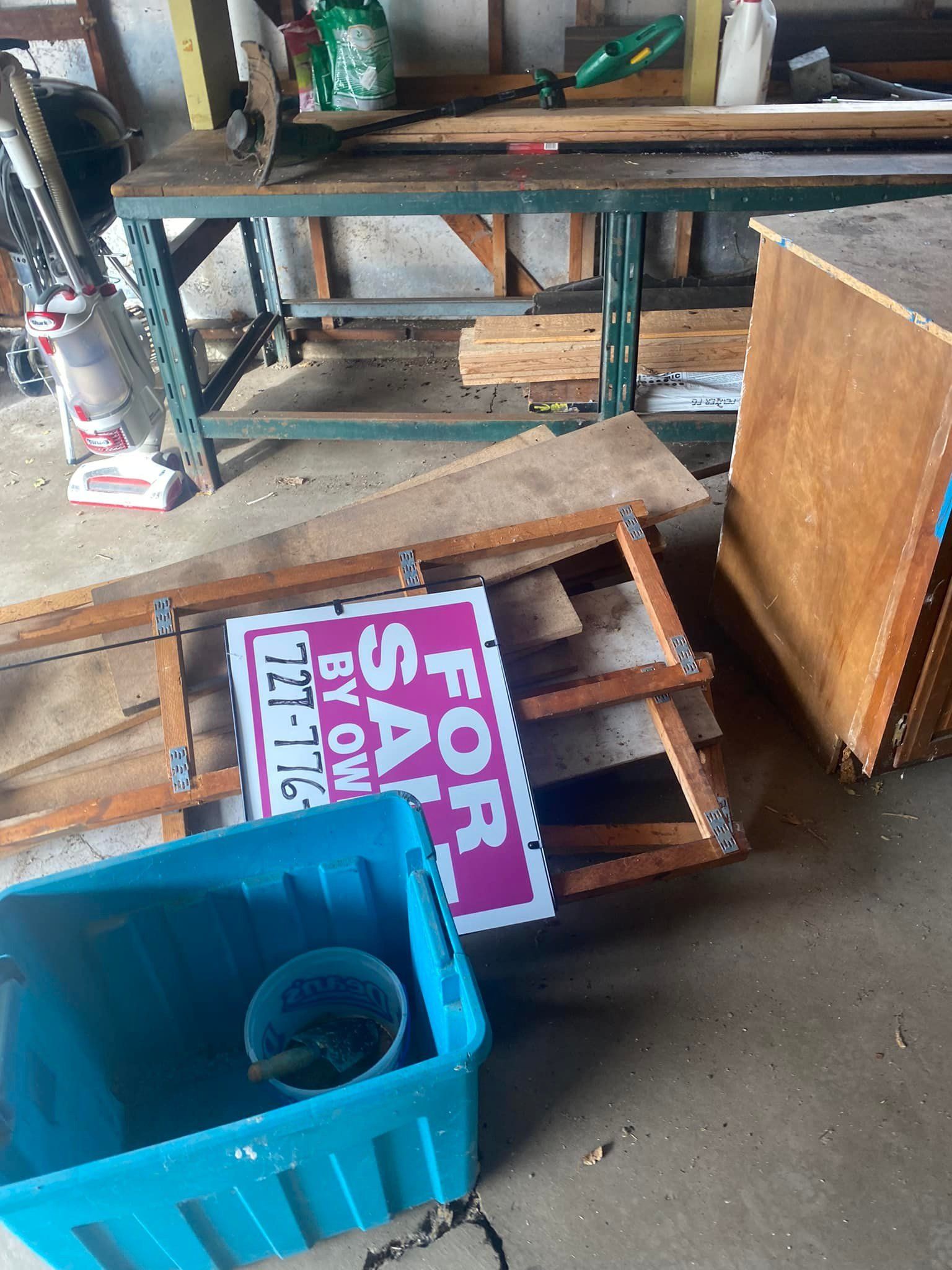 A for sale sign is sitting on top of a pile of wood.