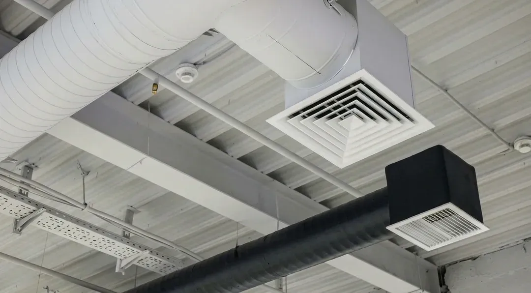 Two ventilation duct systems with grilles under ceiling in commercial building.