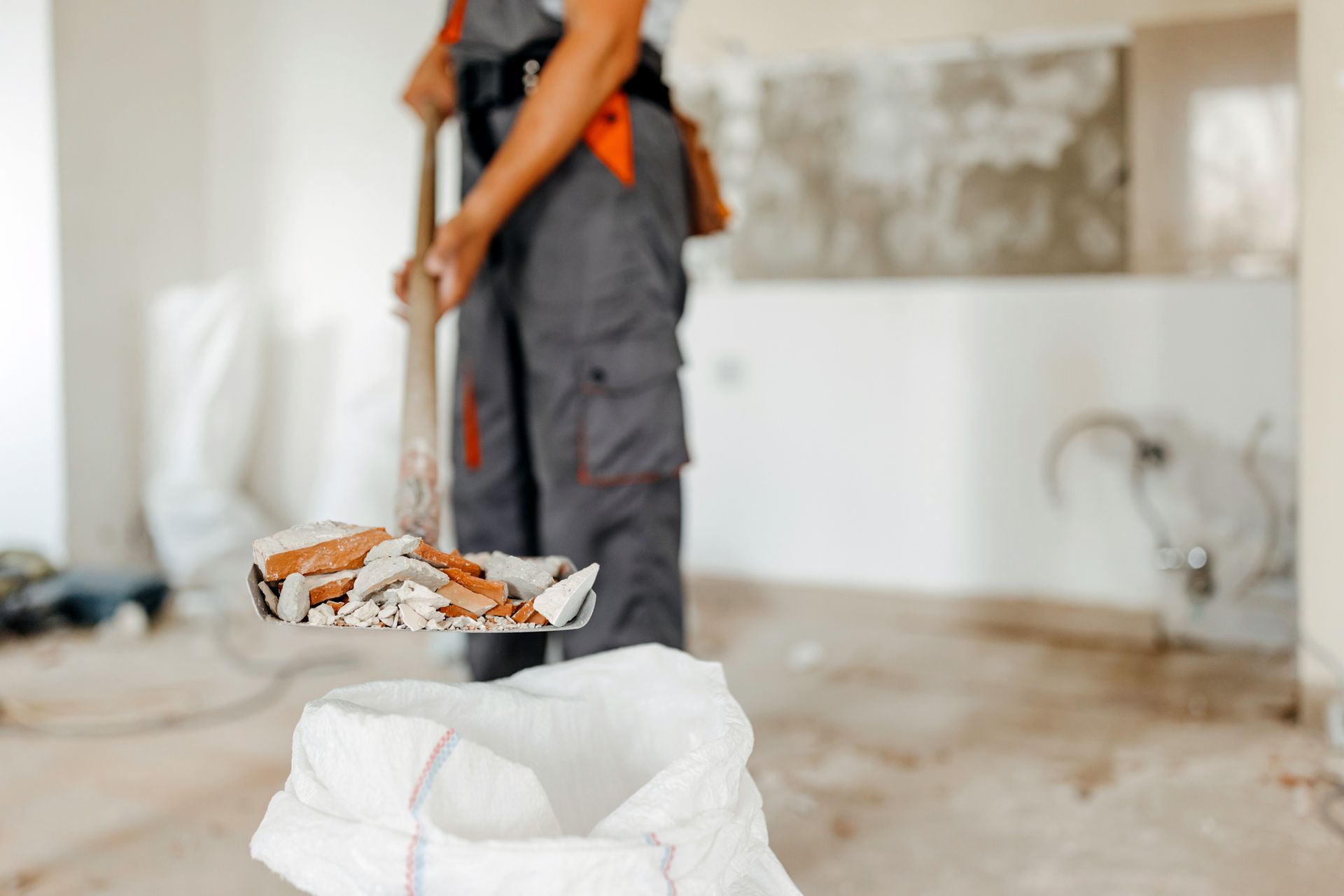 A close up of an unrecognized man holding a shovel filled with construction residue.
