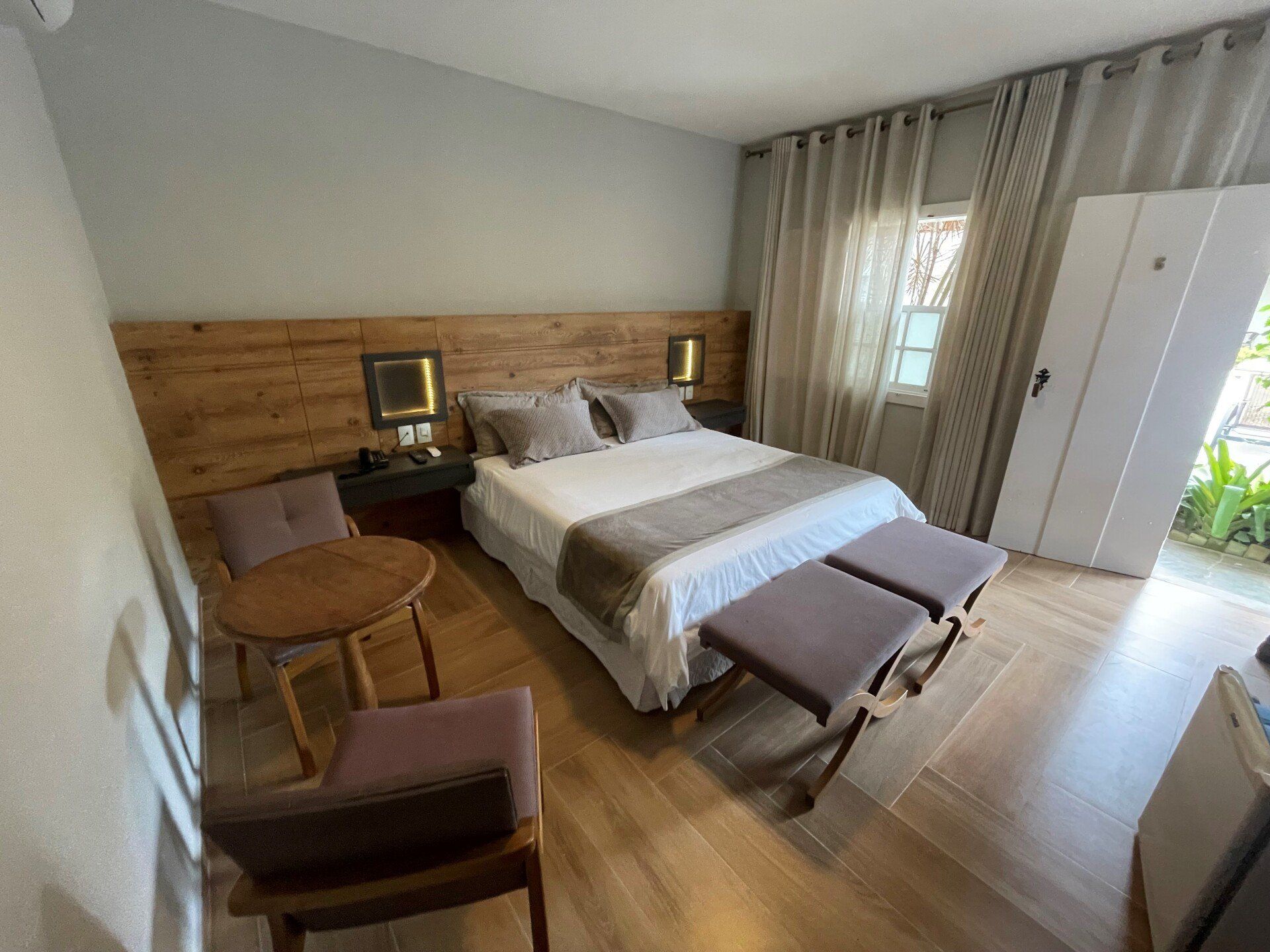 Um quarto de hotel com uma cama, cadeiras, pufes e uma mesa.