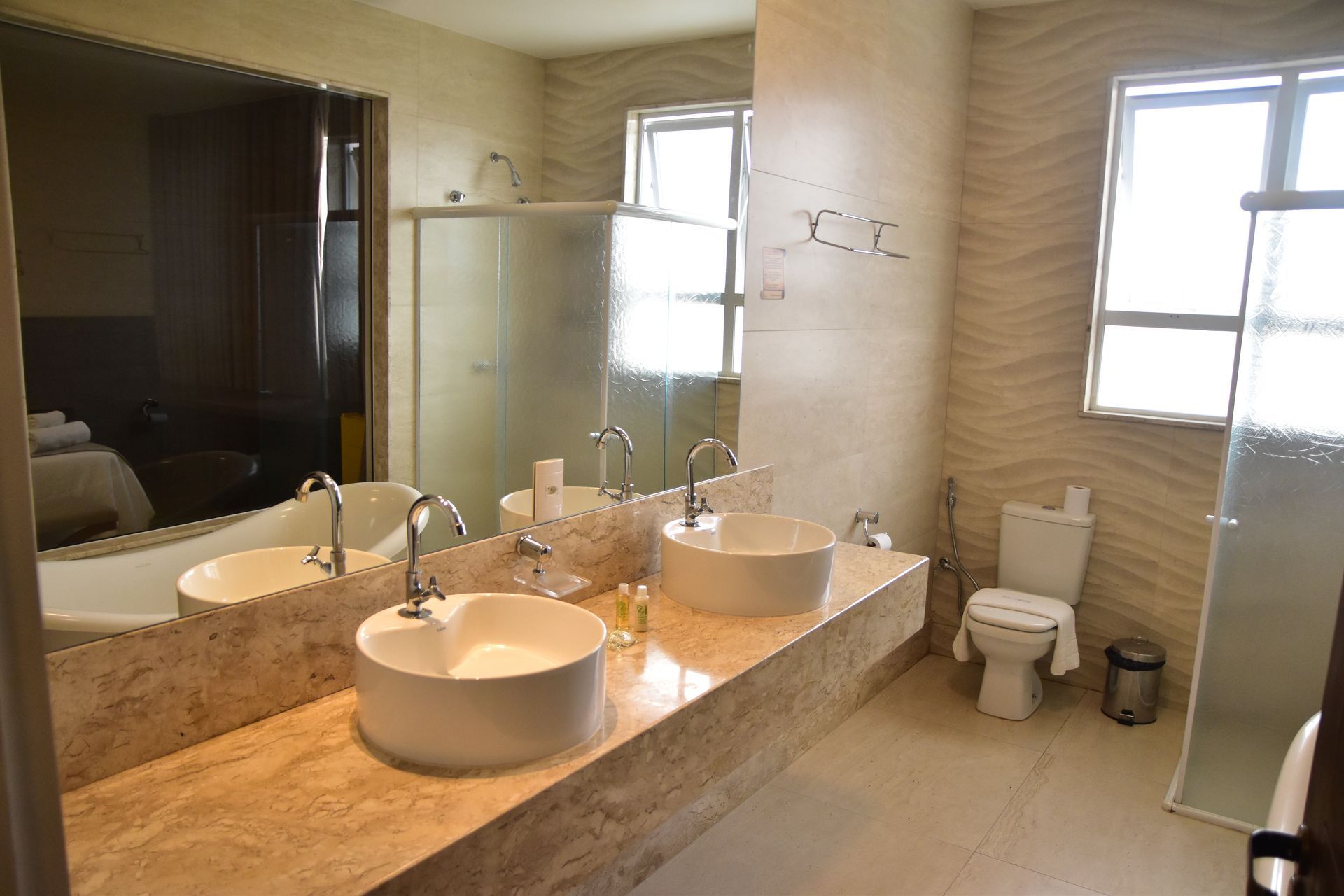 Um banheiro com duas pias, um vaso sanitário e um espelho grande.