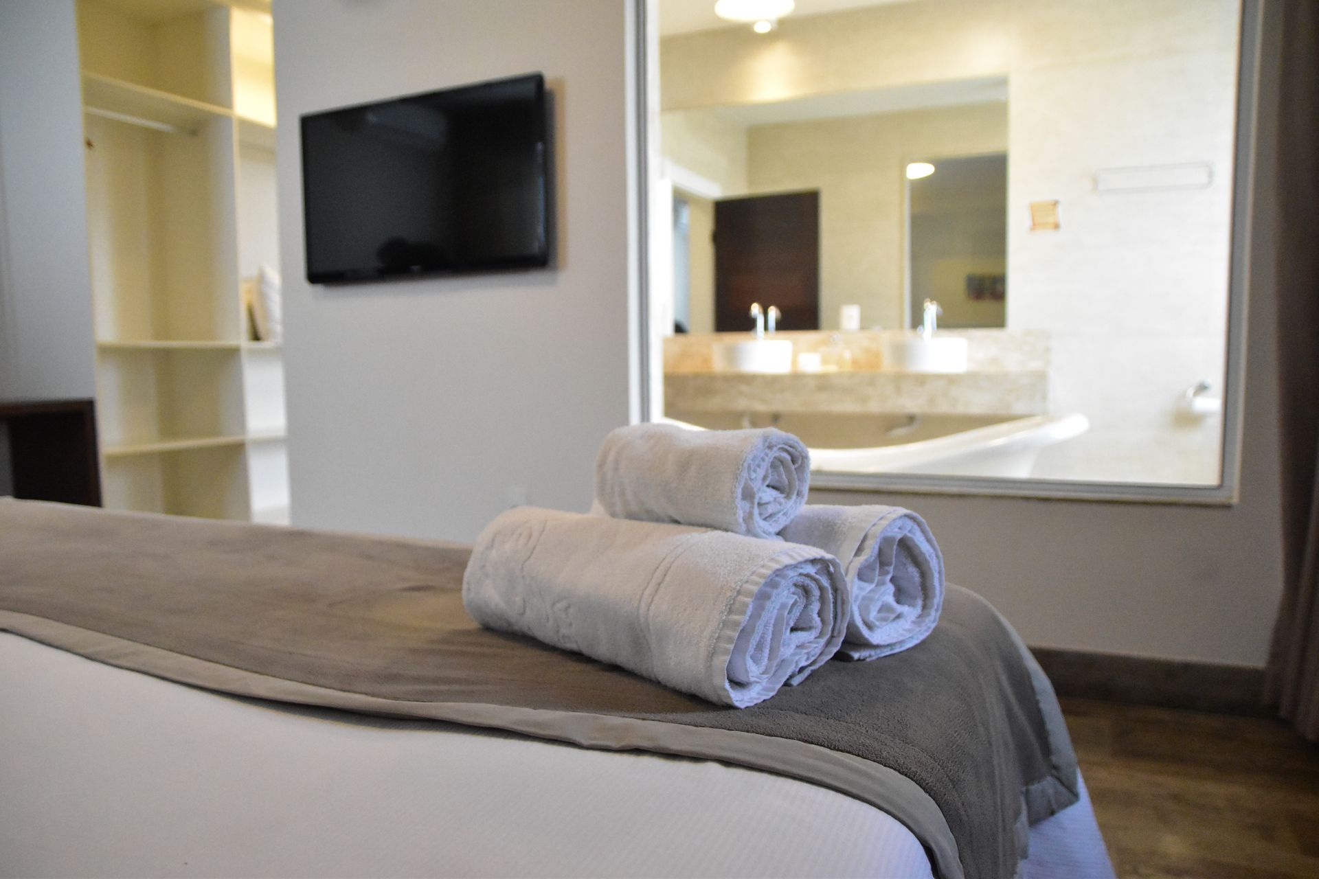Um quarto de hotel com uma cama, televisão e toalhas na cama.