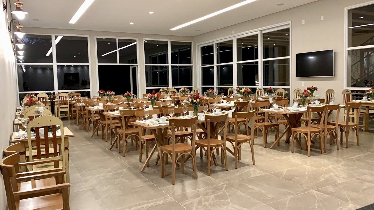 Uma sala grande cheia de mesas, cadeiras e uma televisão.