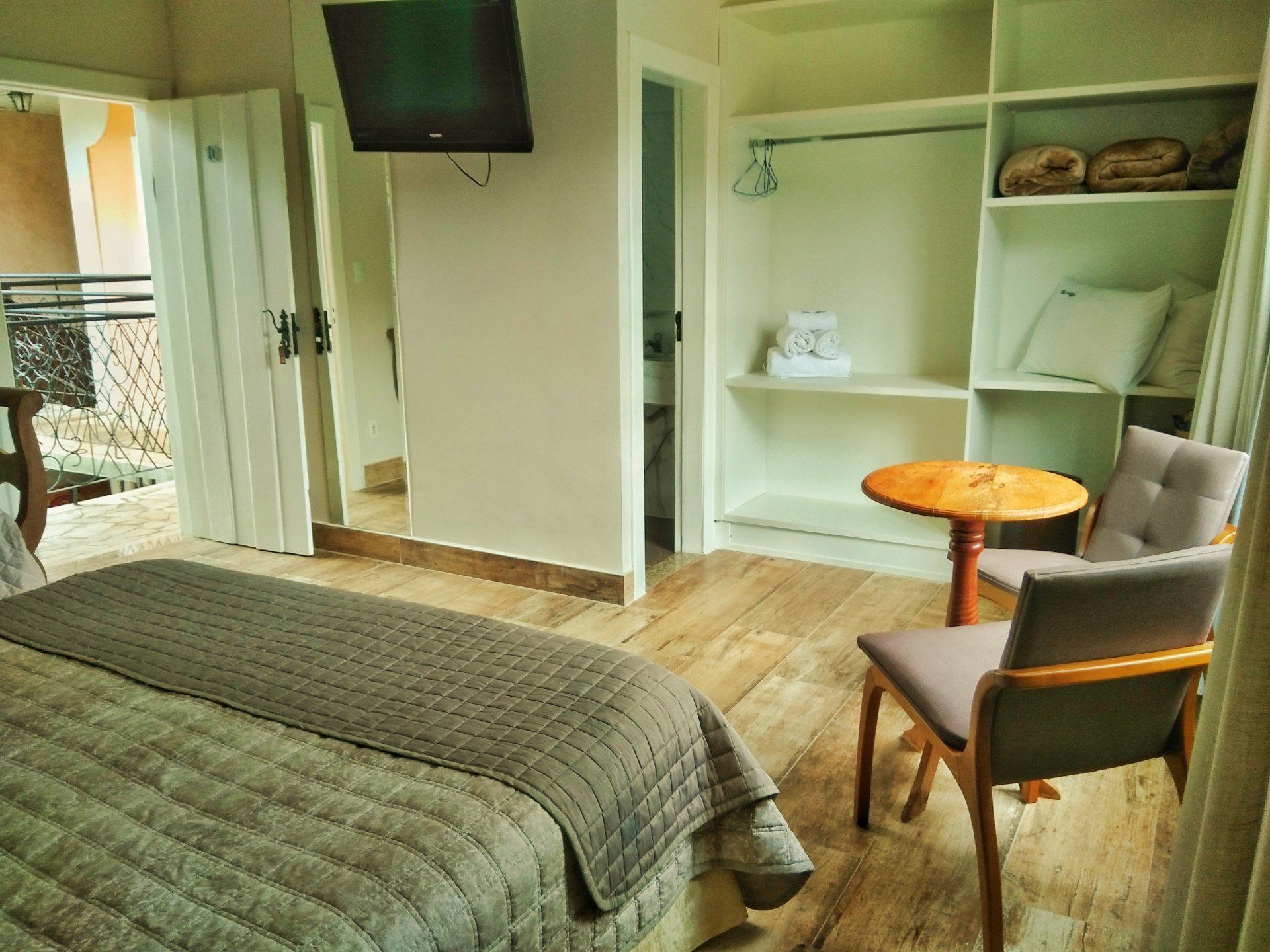 Um quarto de hotel com uma cama, cadeira, mesa e televisão.
