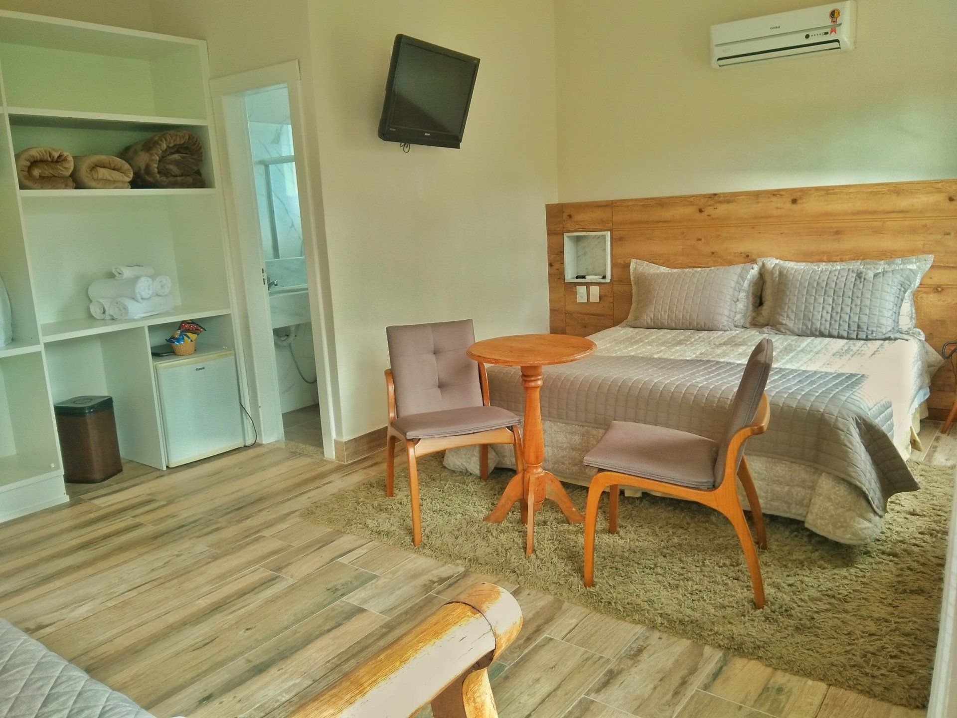 Um quarto de hotel com uma cama, cadeiras, uma mesa e uma televisão.