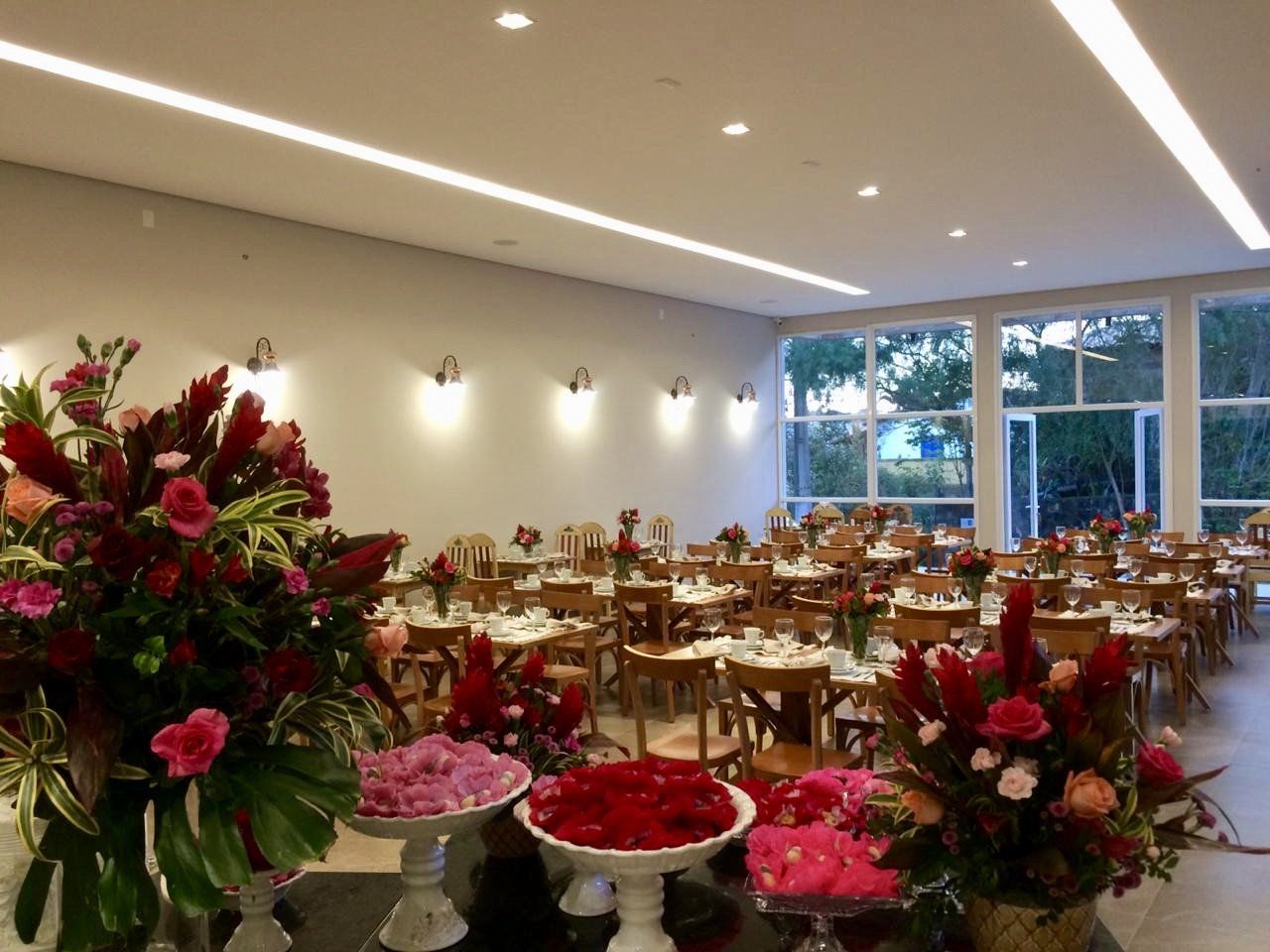 Uma grande sala cheia de mesas, cadeiras e flores.