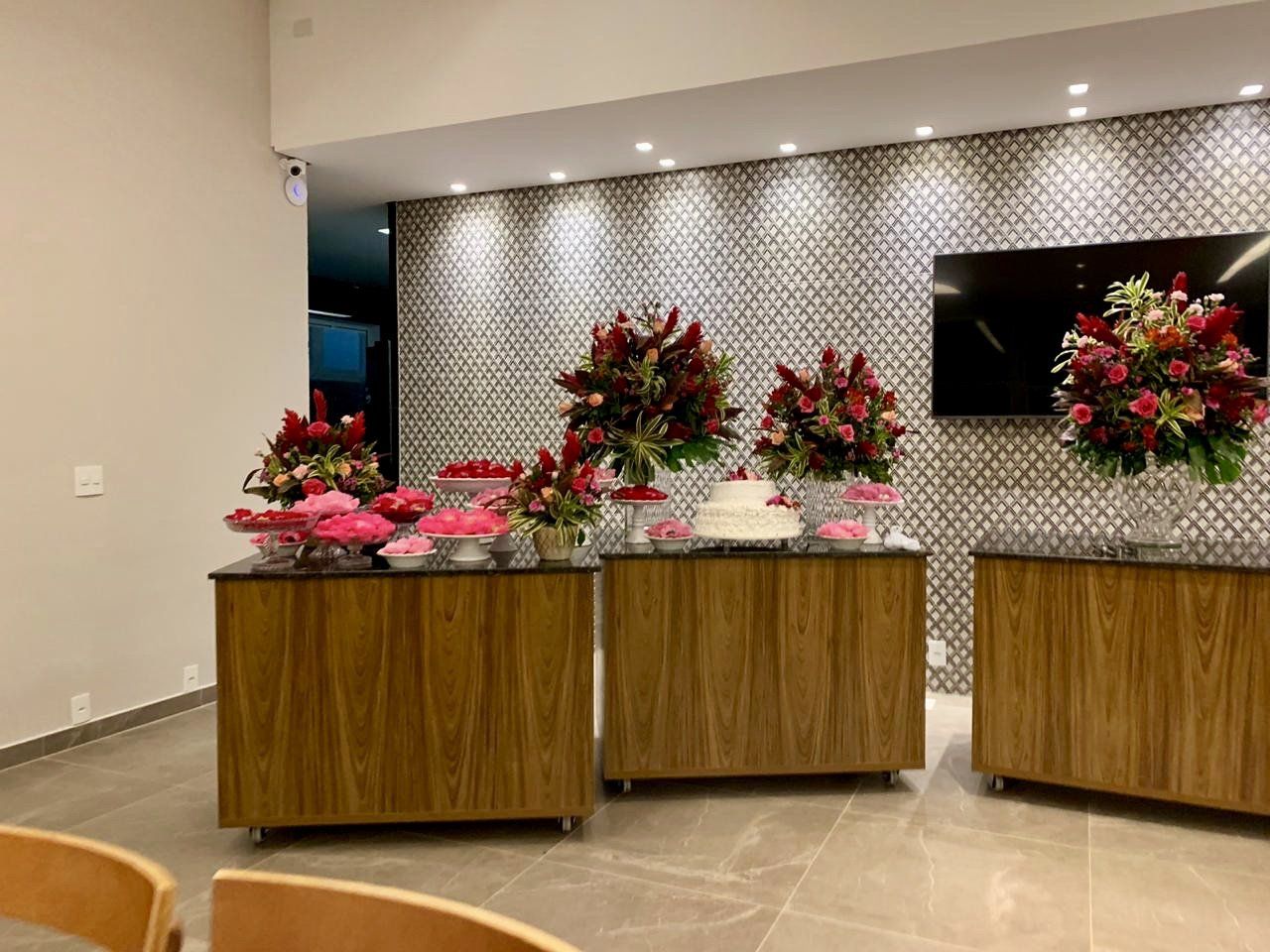 Uma sala com duas mesas de madeira e uma TV na parede.