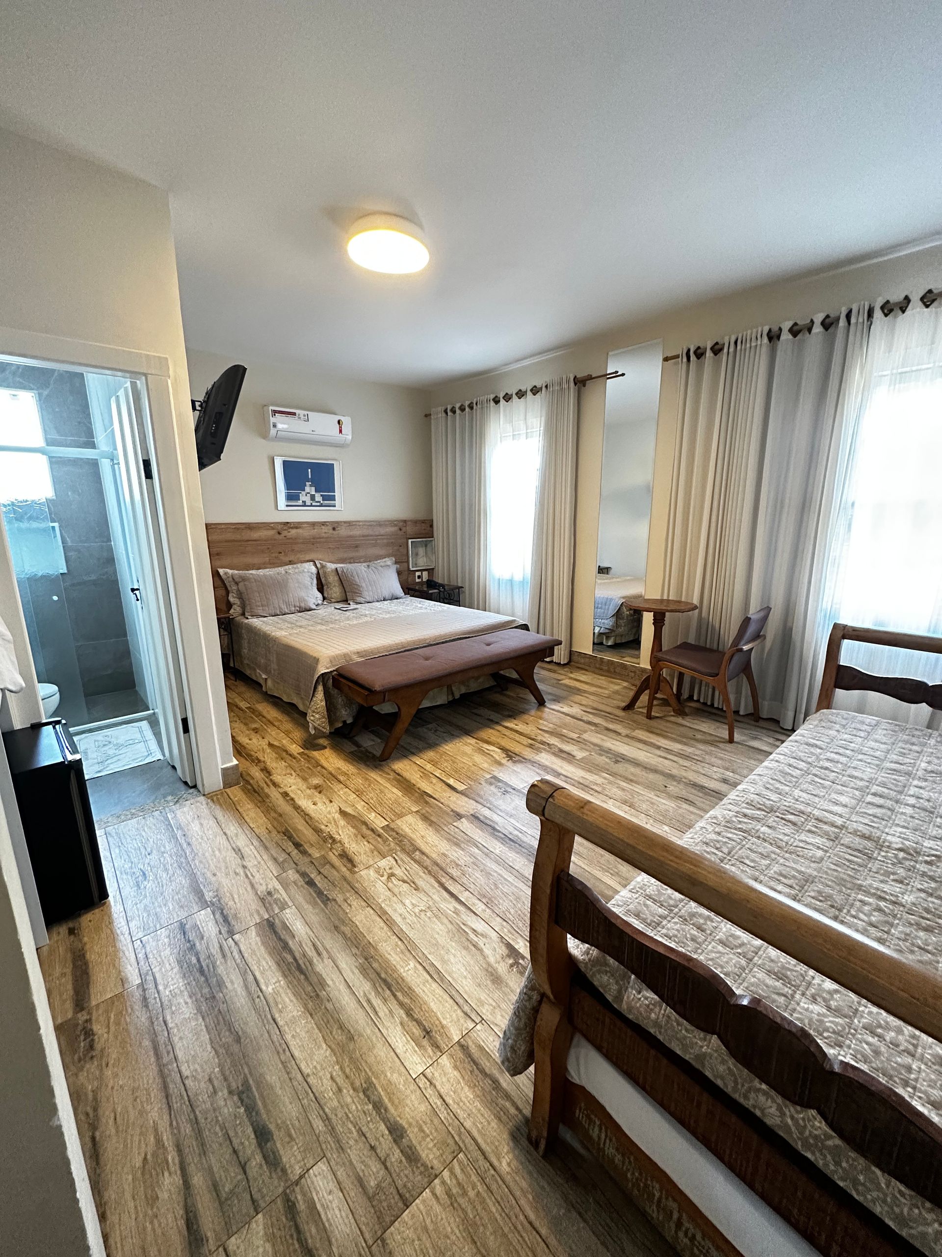 Um quarto grande com duas camas, um banco e um banheiro.