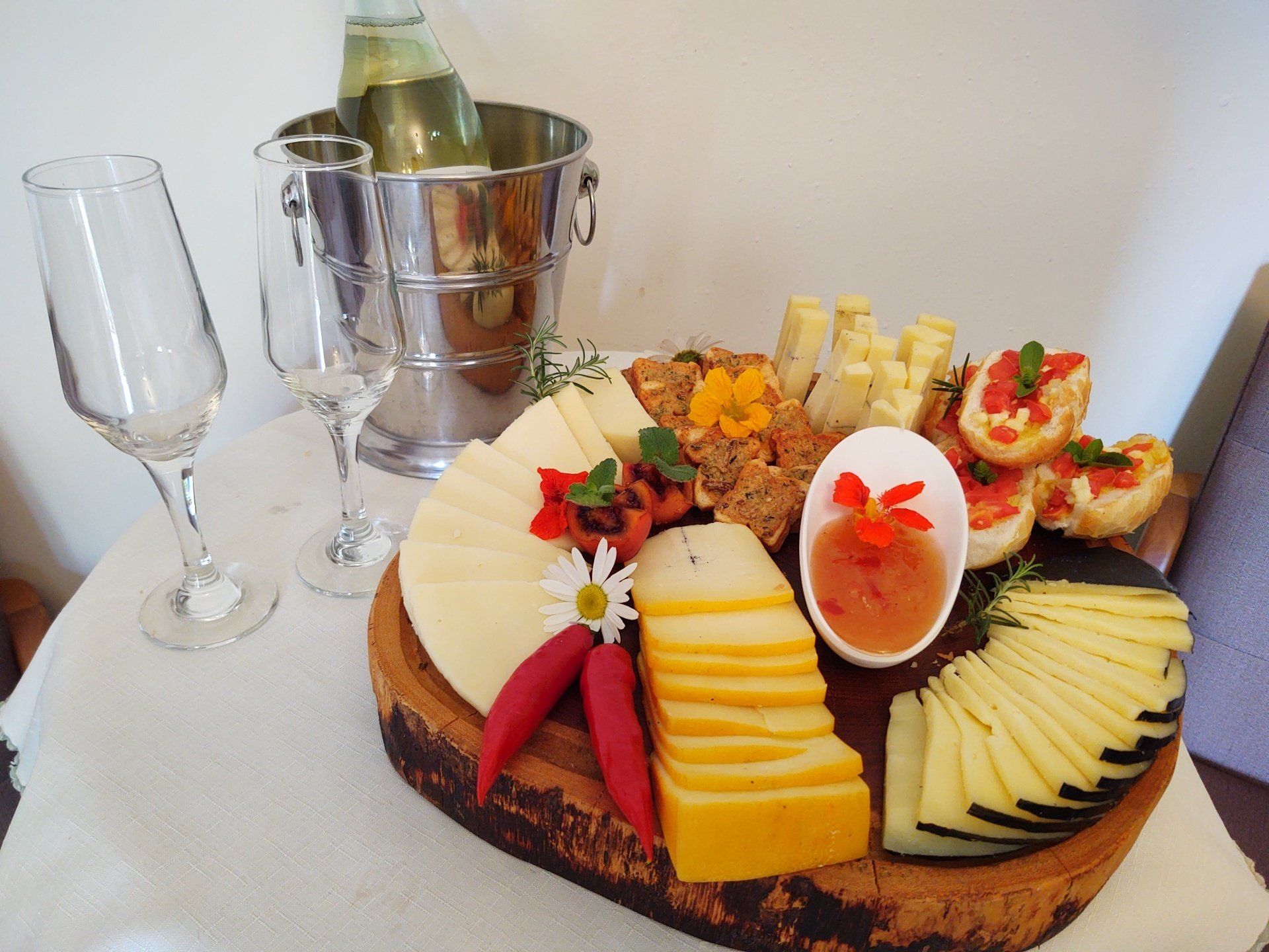 Uma tábua de corte de madeira com queijo e um balde de vinho