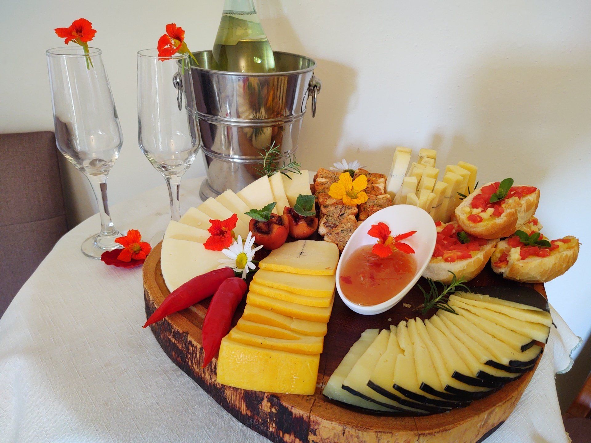Uma tábua de corte de madeira com fatias de queijo e um balde de vinho sobre uma mesa.