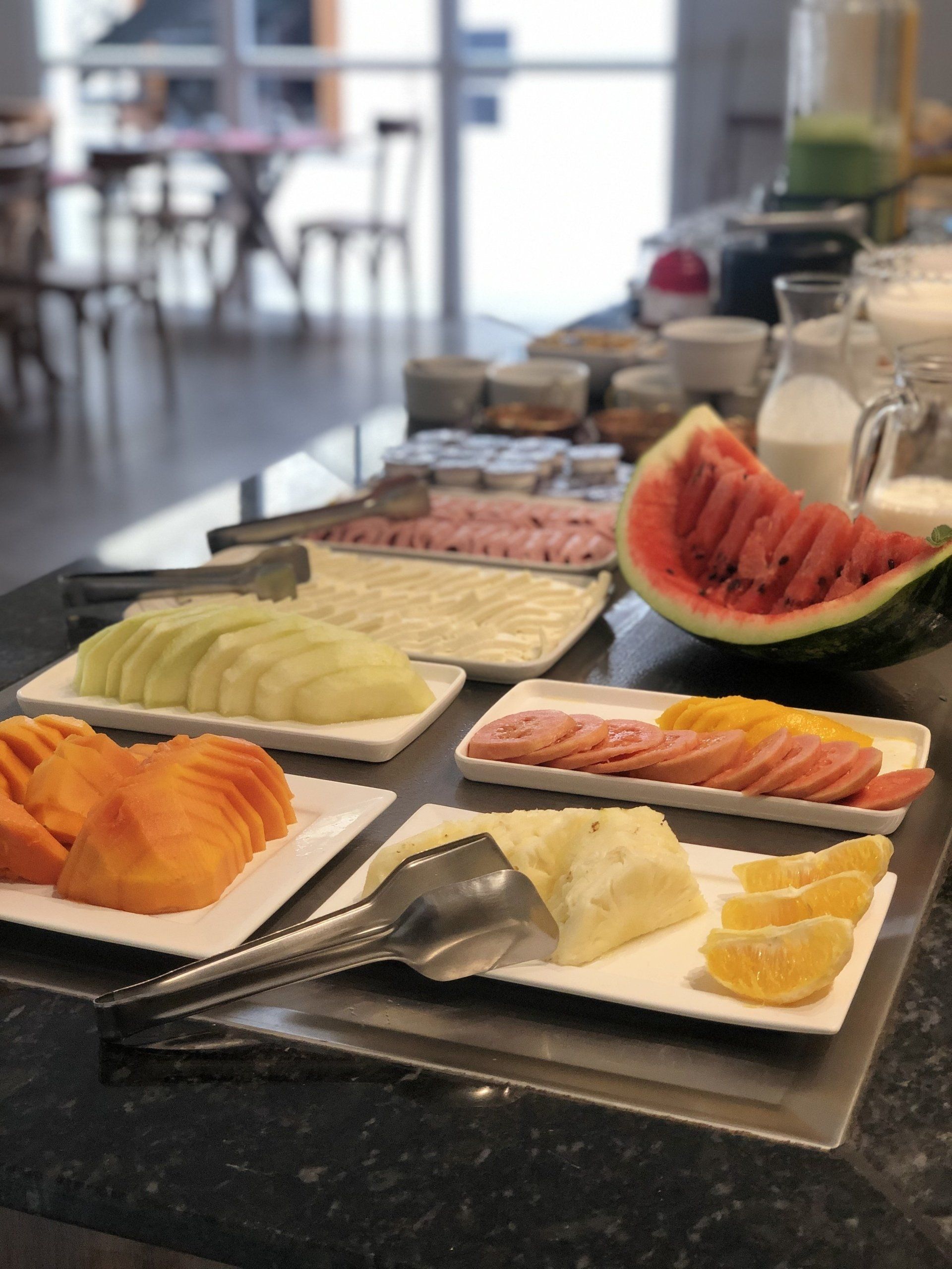 Uma mesa com pratos de frutas e uma melancia sobre ela