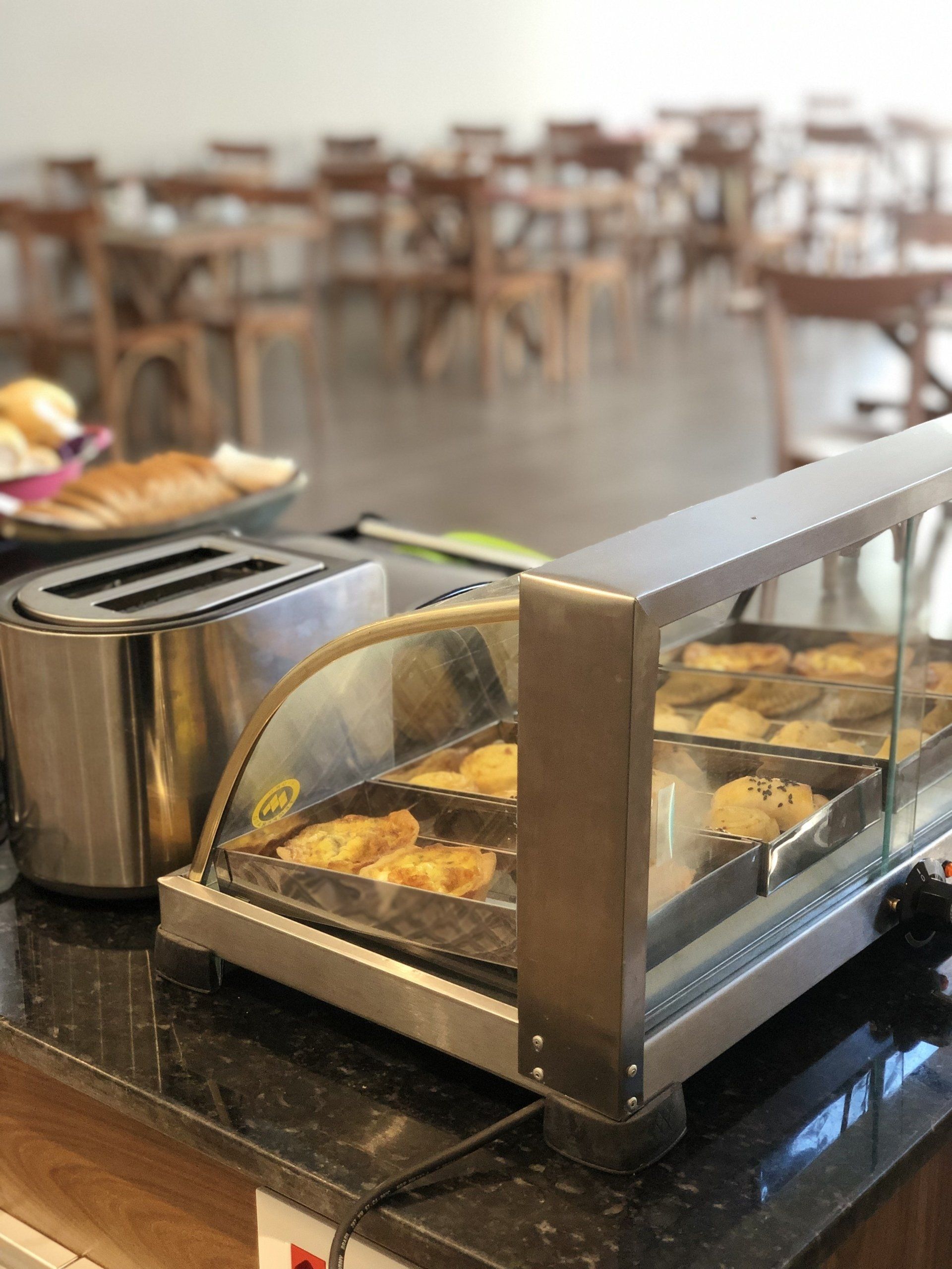 Uma mesa de bufê com uma torradeira e uma vitrine cheia de comida.