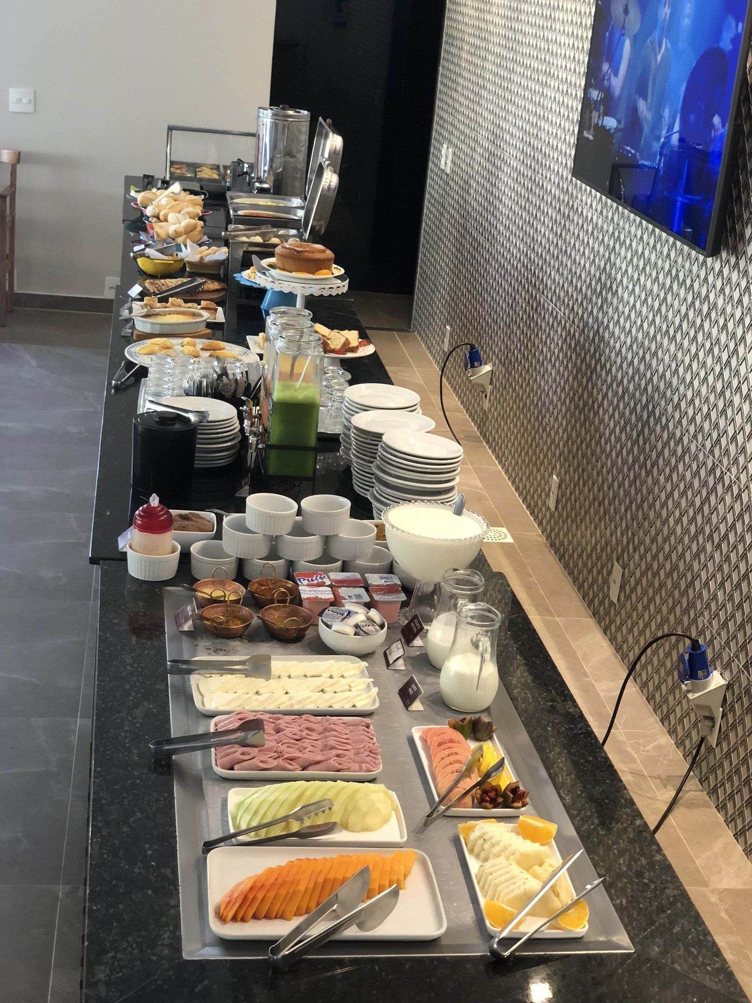 Uma longa mesa de bufê cheia de comida e bebidas.