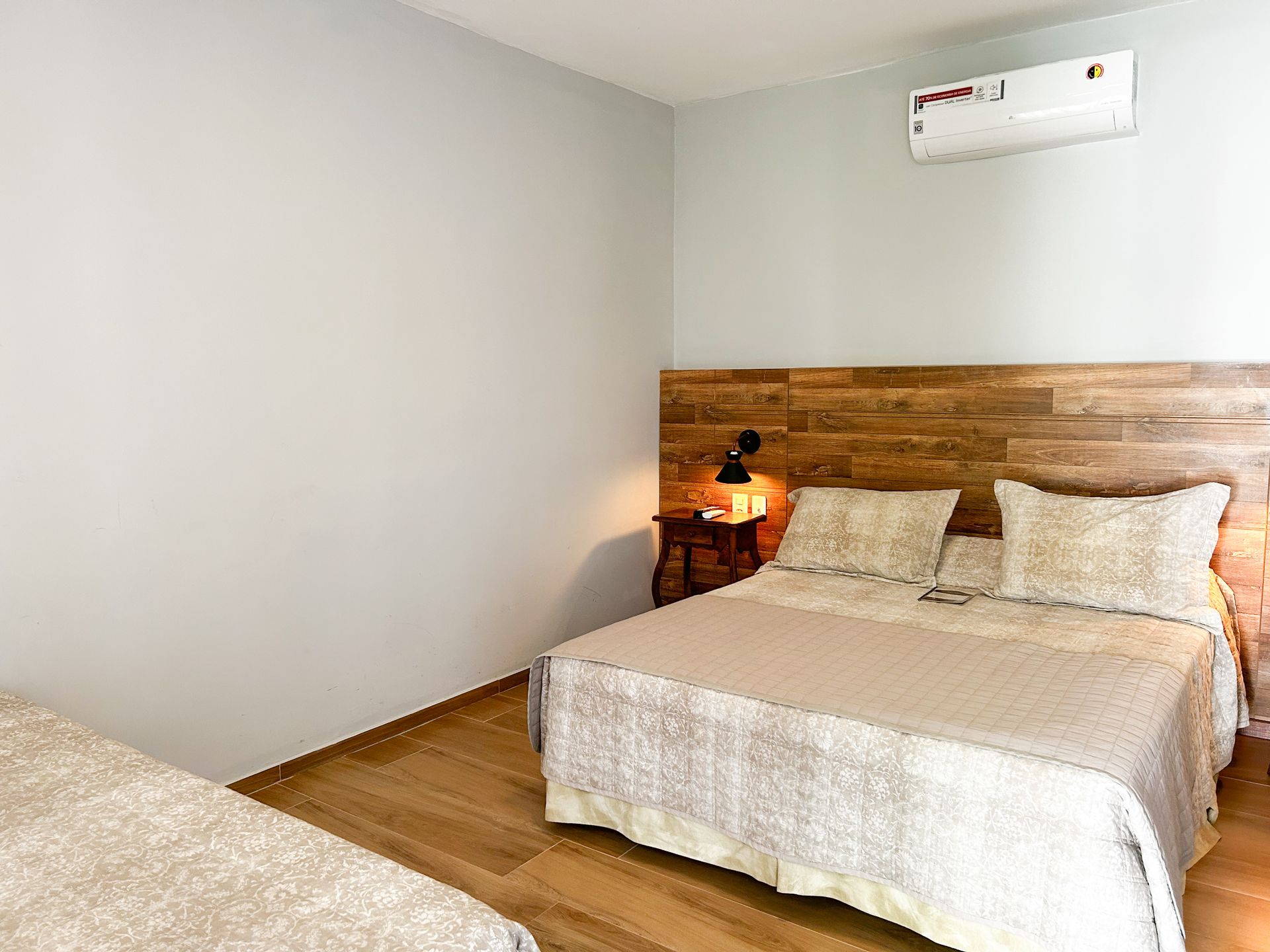 Um quarto com duas camas e uma cabeceira de madeira.