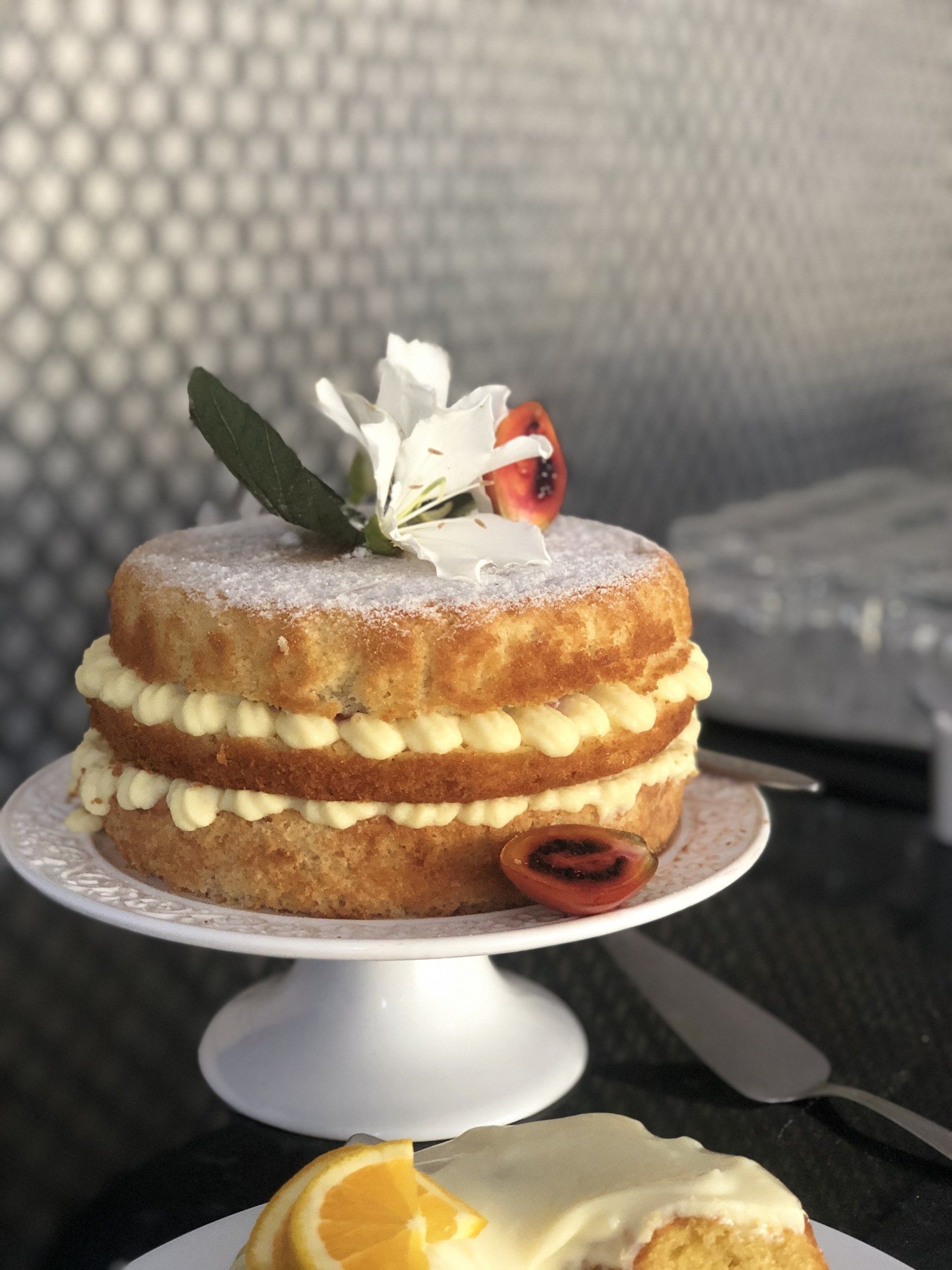 Um bolo com açúcar de confeiteiro e uma flor no topo