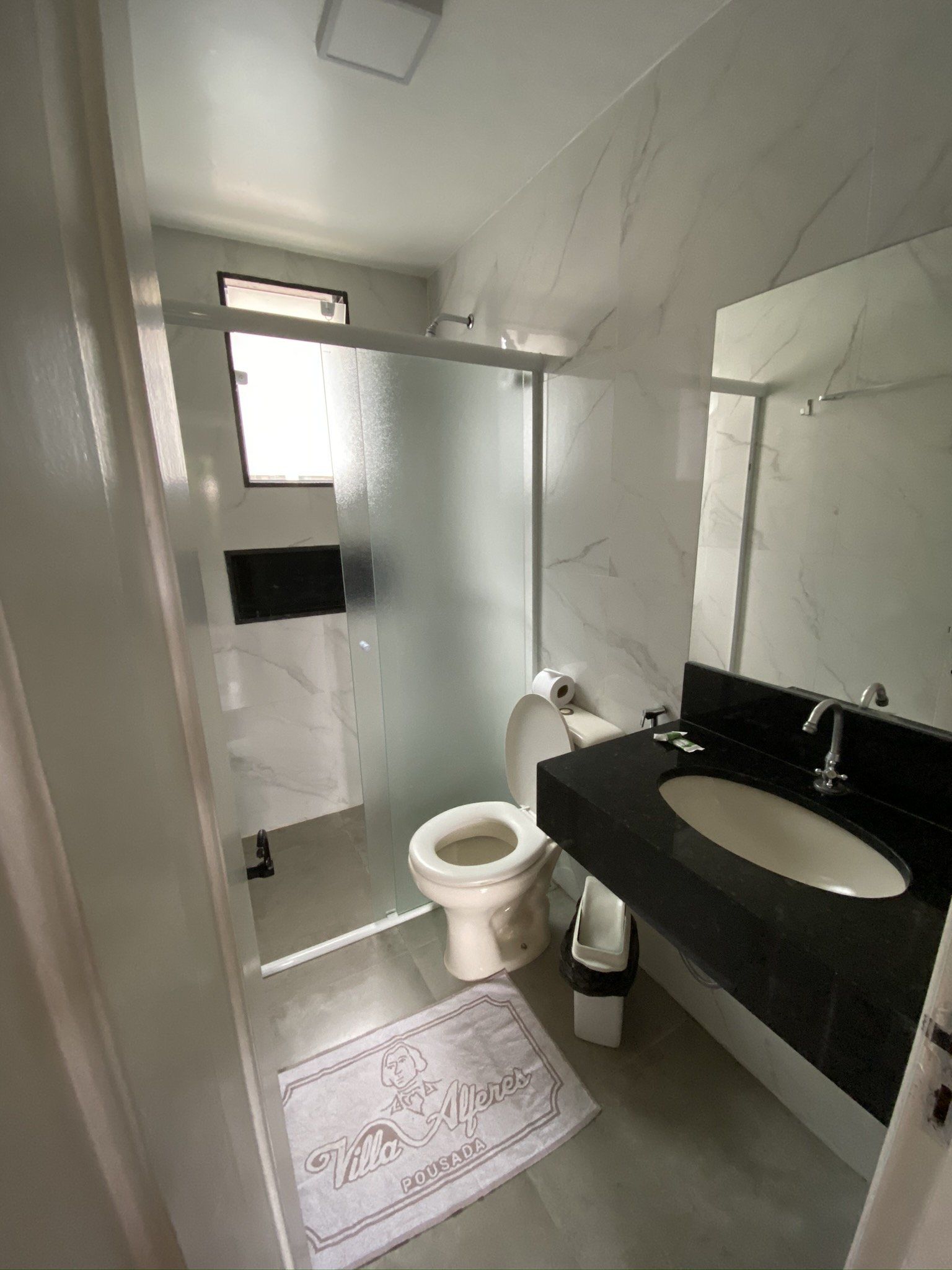 Um banheiro com vaso sanitário, pia e chuveiro.