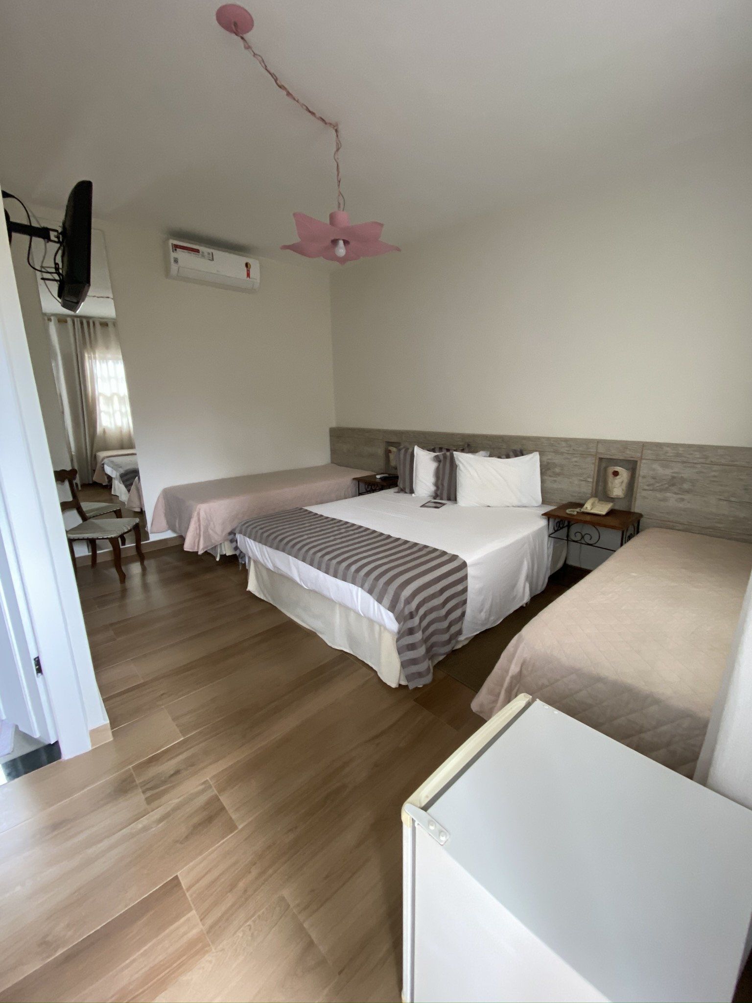 Um quarto de hotel com três camas e uma televisão.