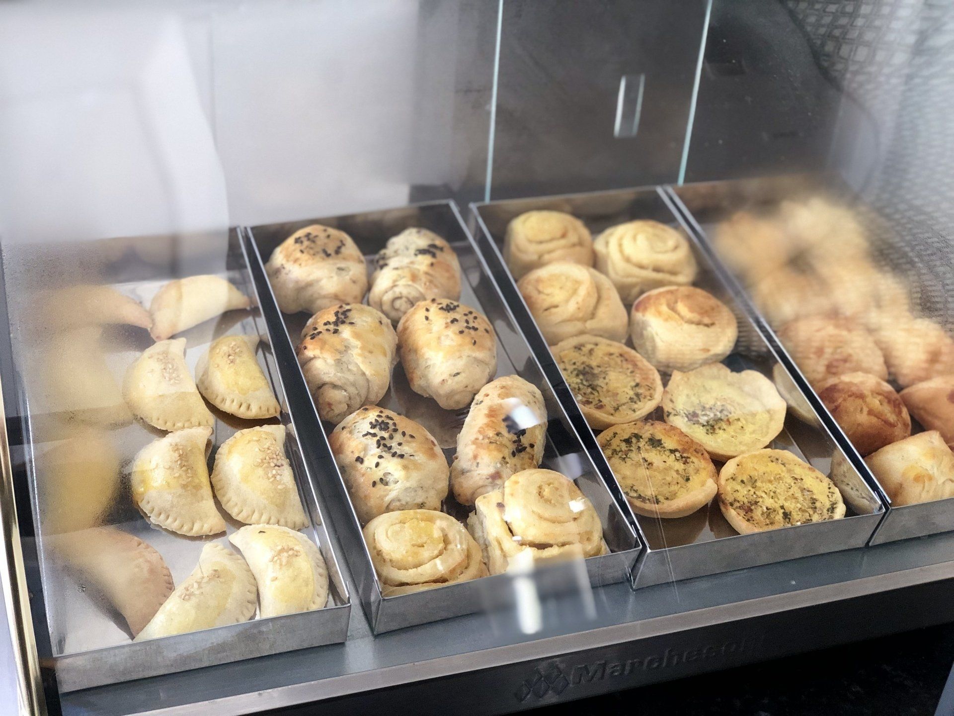 Uma variedade de doces são expostos em uma vitrine de vidro.