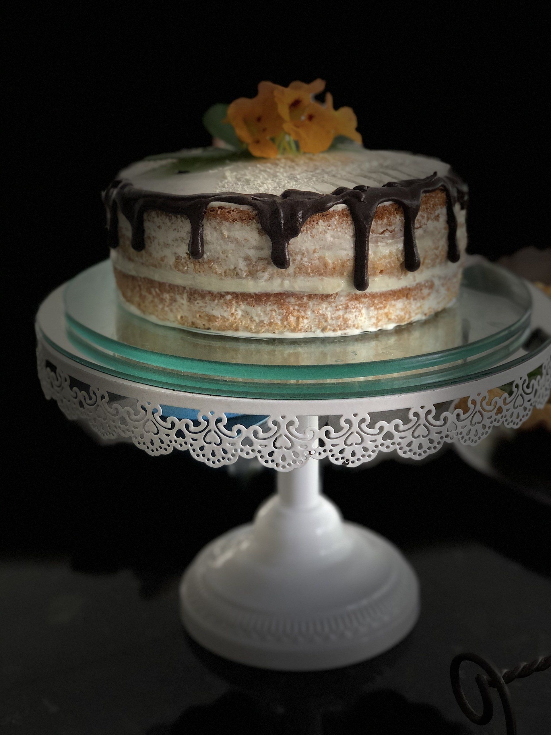 Um bolo em um suporte de bolo com uma flor no topo