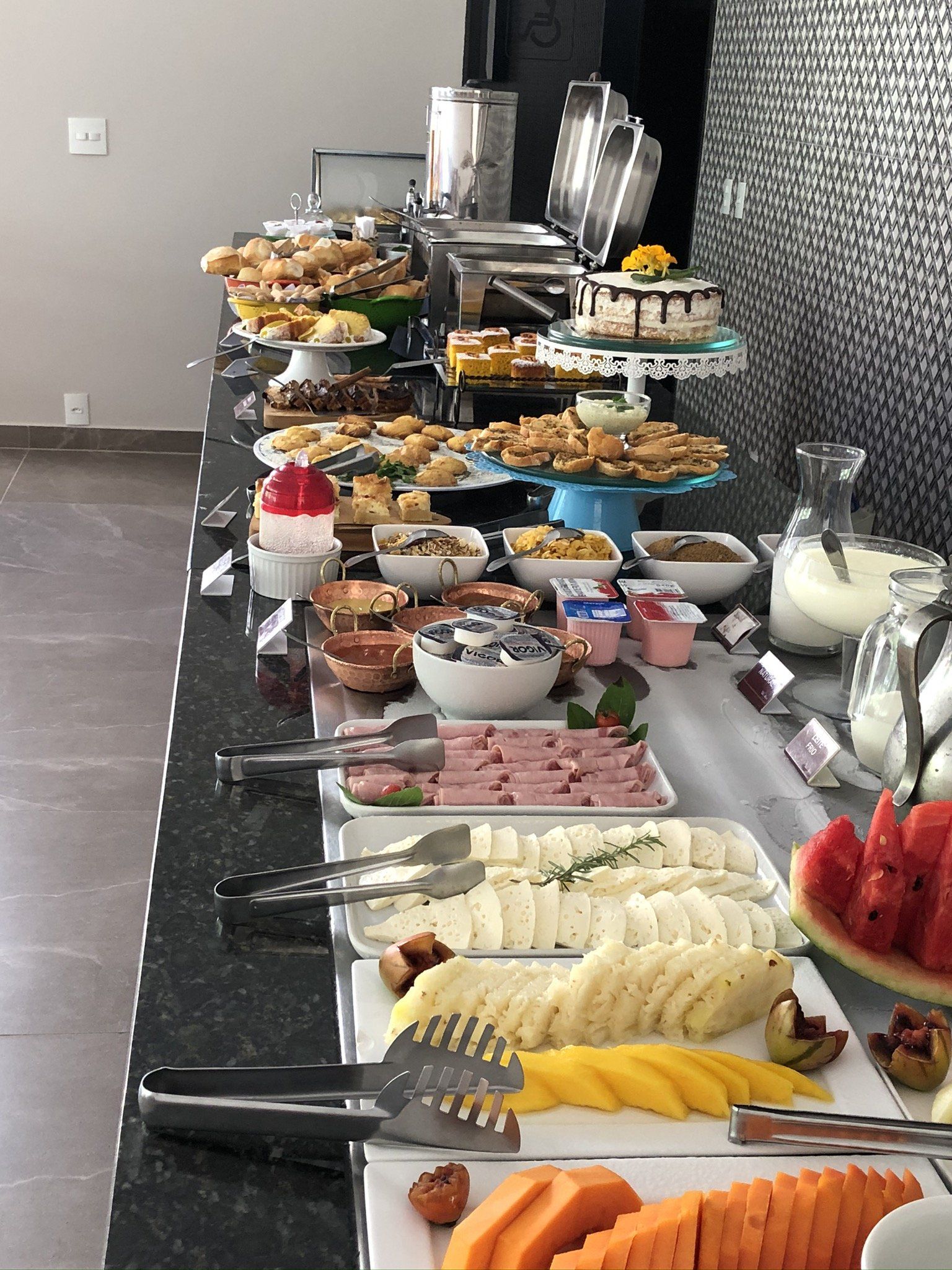 Uma longa mesa de bufê com uma variedade de comidas.