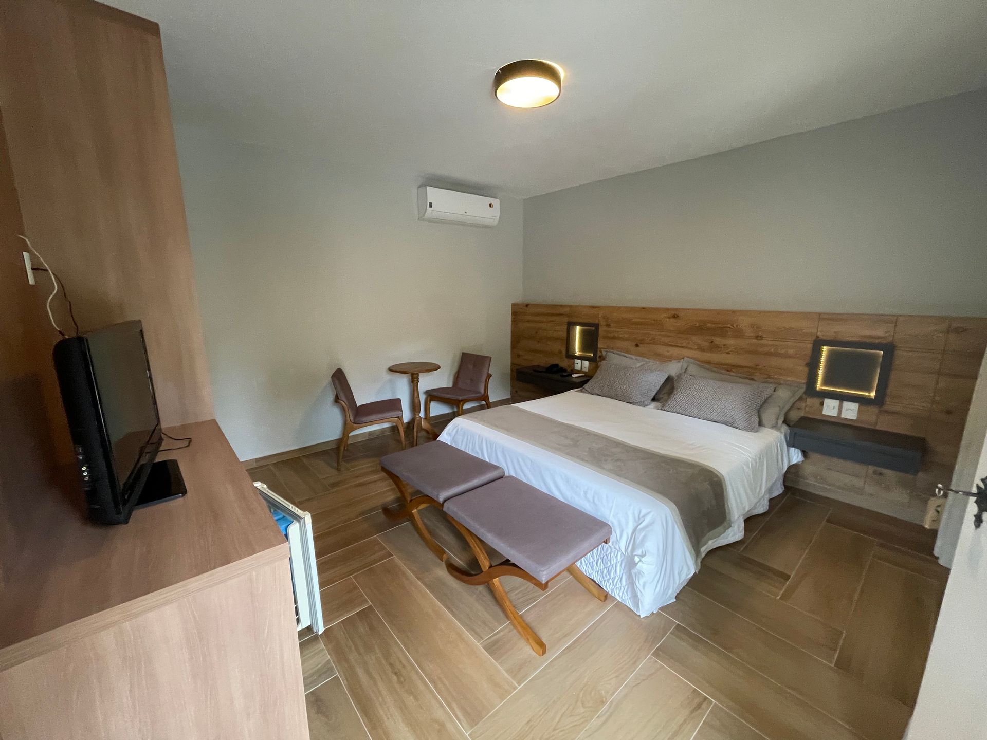 Um quarto de hotel com uma cama king size, mesa e cadeiras.