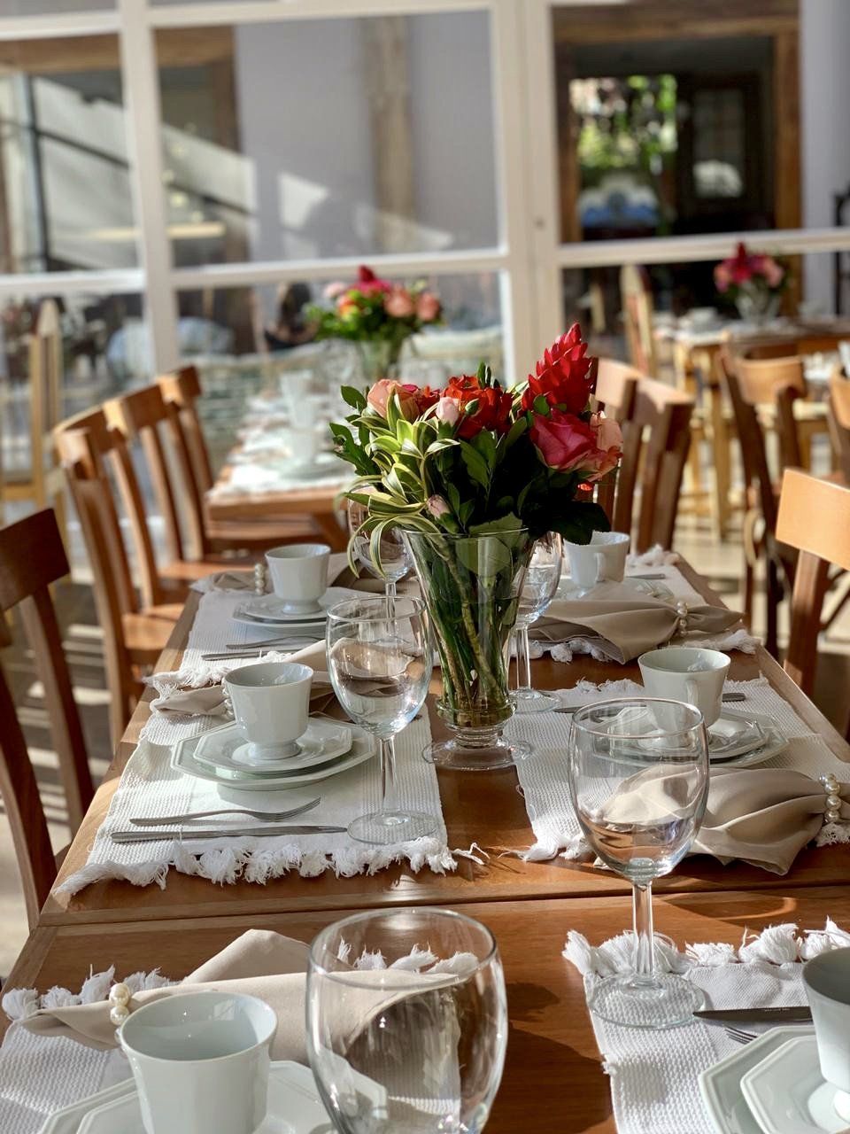 Uma mesa longa com um vaso de flores sobre ela.