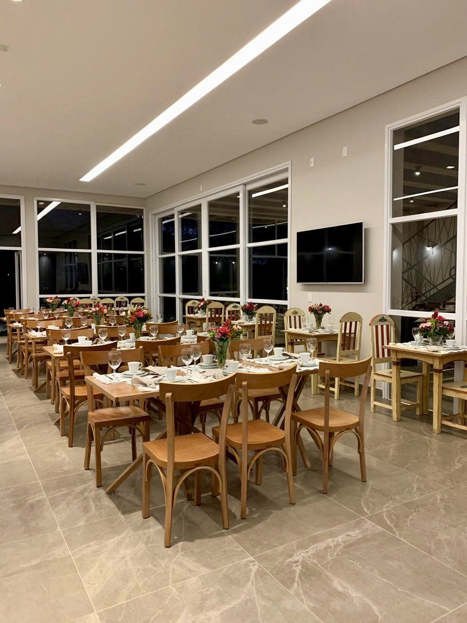 Uma grande sala de jantar com mesas e cadeiras e uma TV de tela plana.