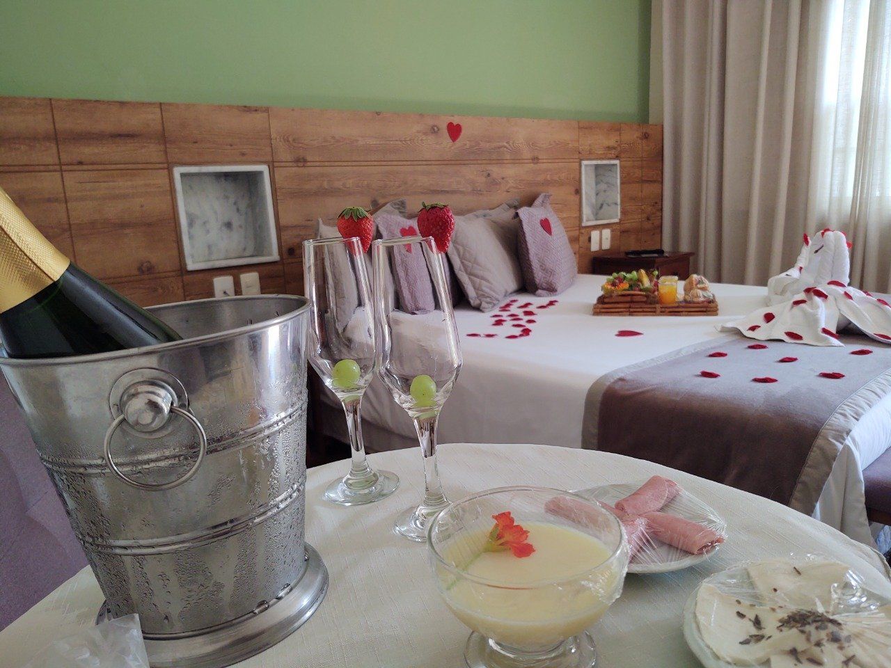 Um quarto de hotel com duas camas e uma mesa com um balde de champanhe e taças em cima.