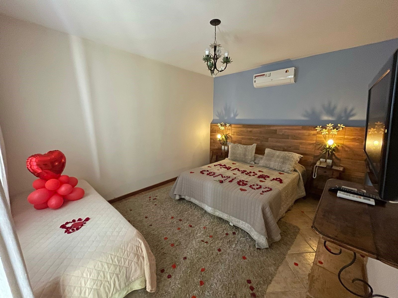 Um quarto com duas camas, uma televisão e um balão em forma de coração na cama.