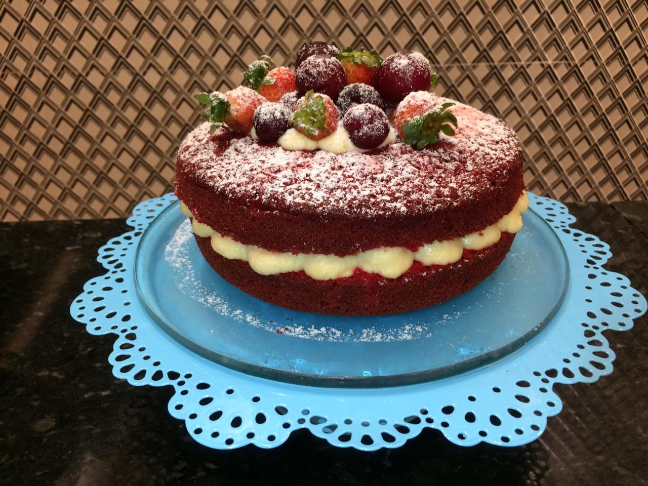 Um bolo de veludo vermelho com morangos e mirtilos no topo