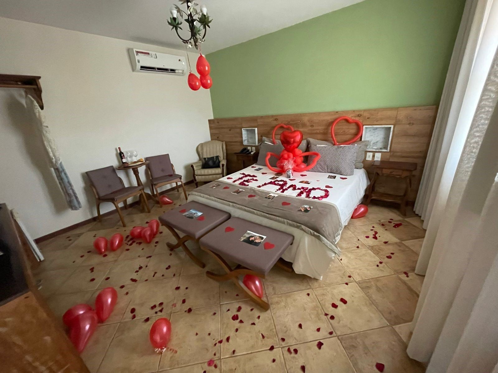 Um quarto de hotel decorado para o dia dos namorados com balões e pétalas de rosa no chão.
