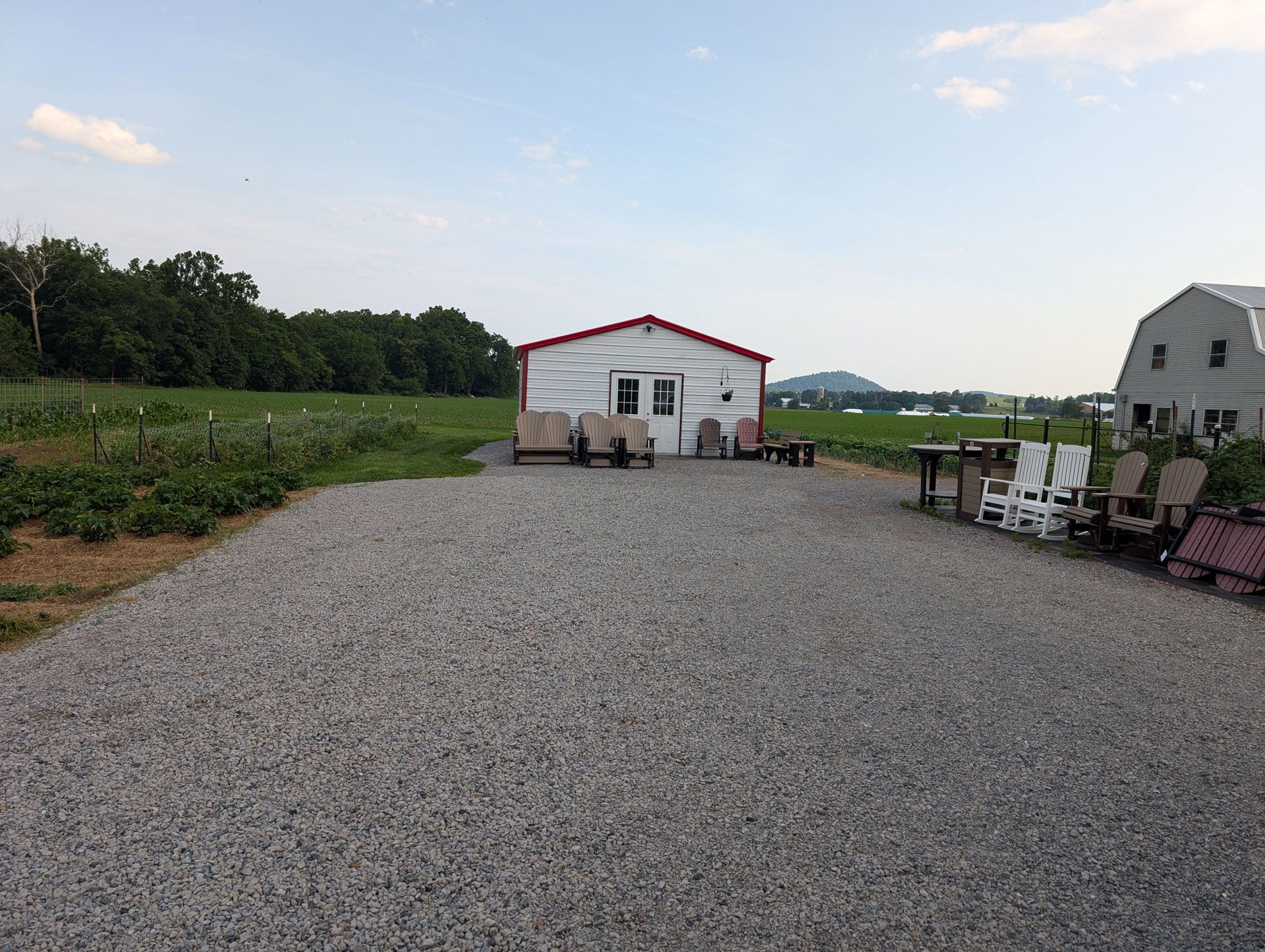 A gravel driveway leading to a white building with a red roof.