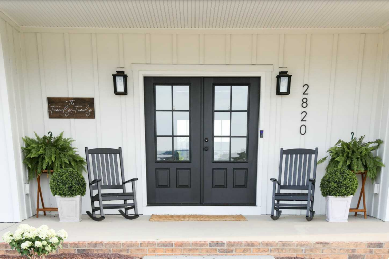 There are two rocking chairs on the porch of a house.