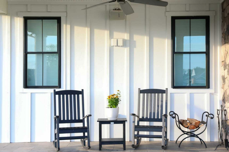 A porch with three rocking chairs and a table