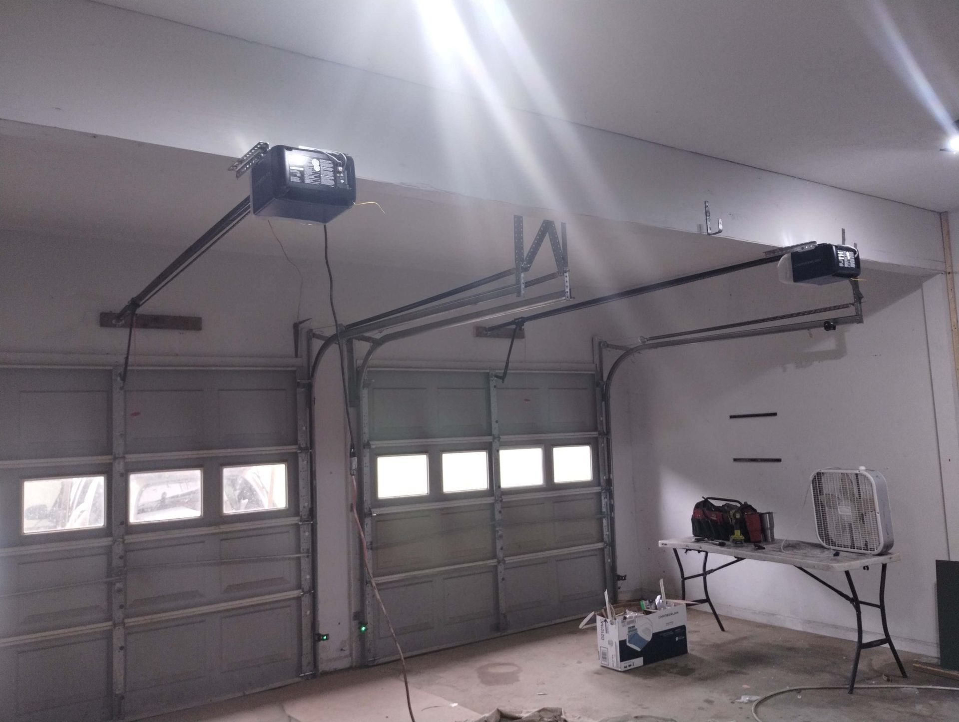 A garage door opener is hanging from the ceiling of a garage.