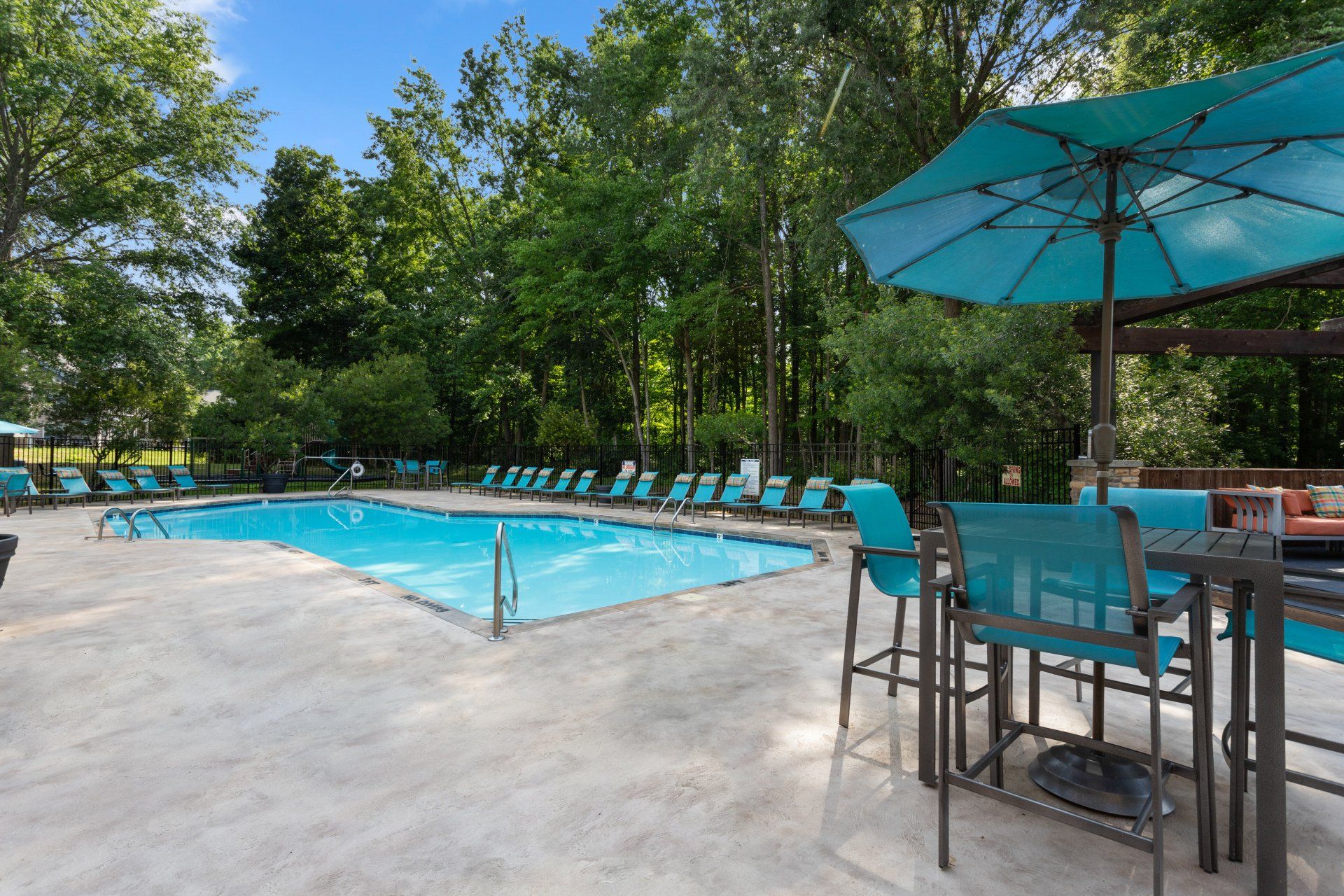 A large swimming pool with a table and chairs under an umbrella Park at Oak Ridge.