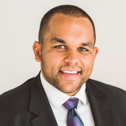 A man is holding a dog in his arms and the dog is wearing a sweater.