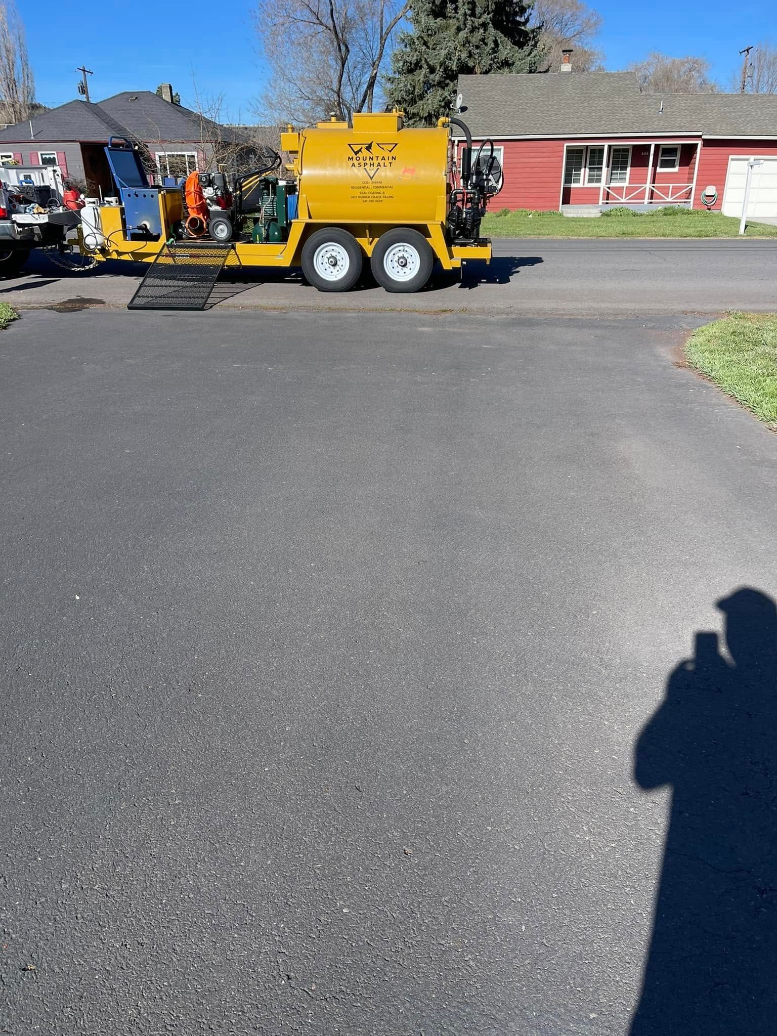 A yellow truck is parked in a driveway next to a red house.