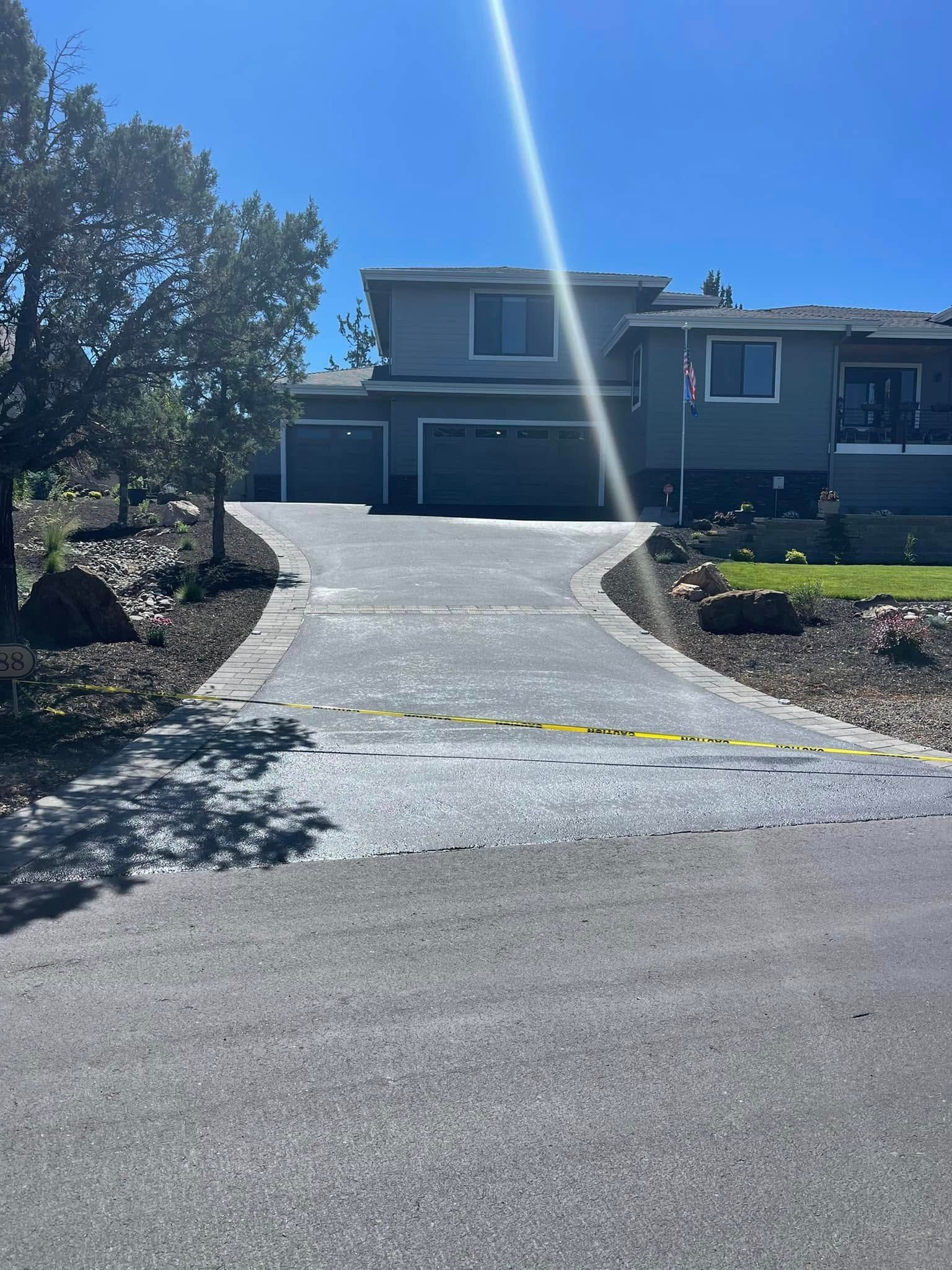 A driveway leading to a large house on a sunny day.