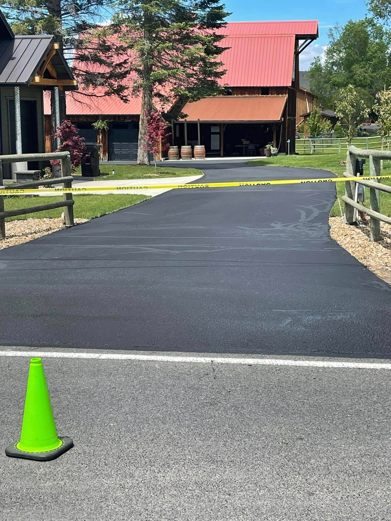 A green traffic cone is sitting on the side of a road in front of a house.